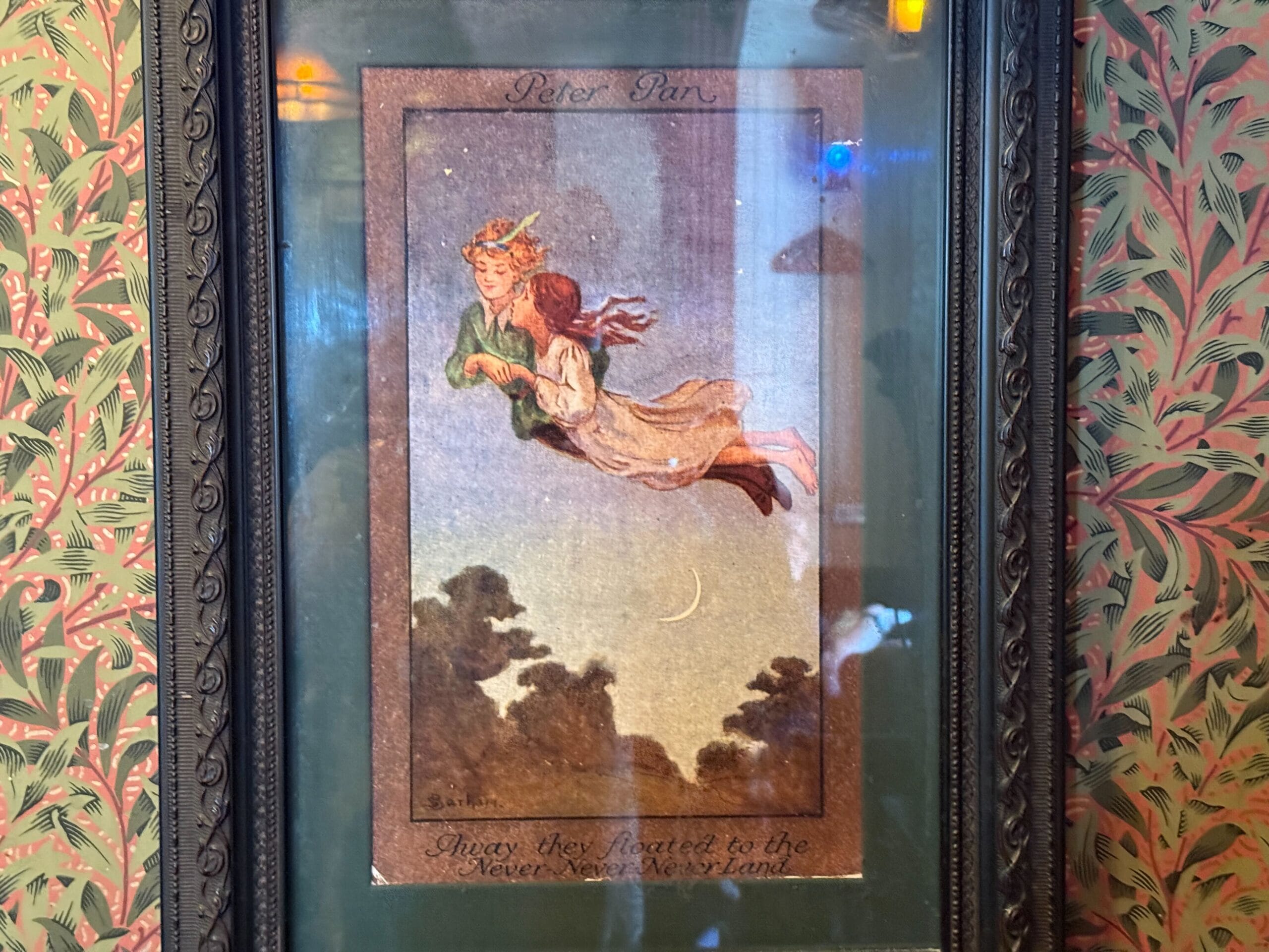 Illustration of Peter Pan flying with Wendy at night, in a frame on leafy wallpaper, reminiscent of scenes from Disney parks.