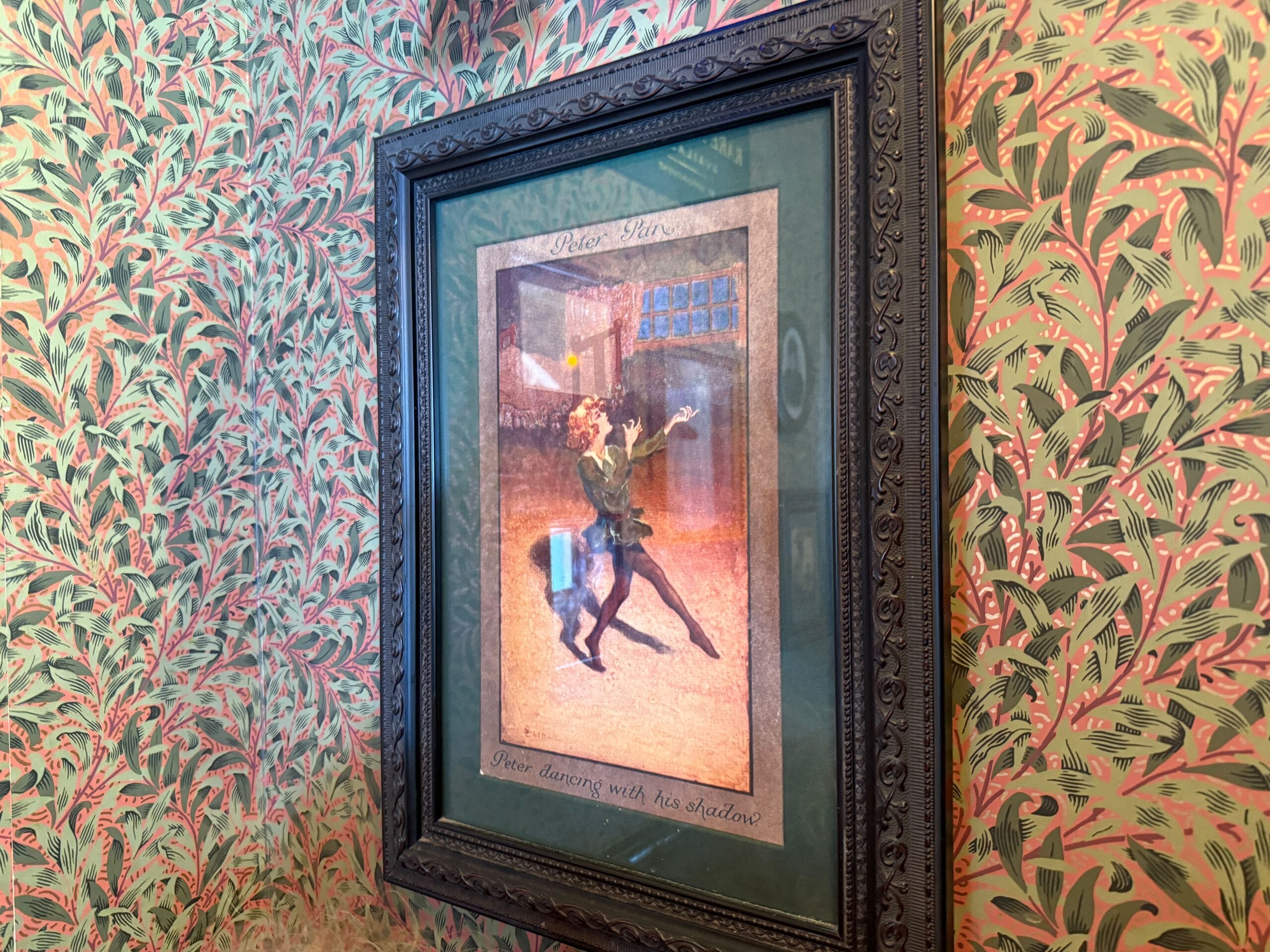 Framed artwork of a man and woman dancing, displayed against pink and green leafy wallpaper reminiscent of Disney resort decor.