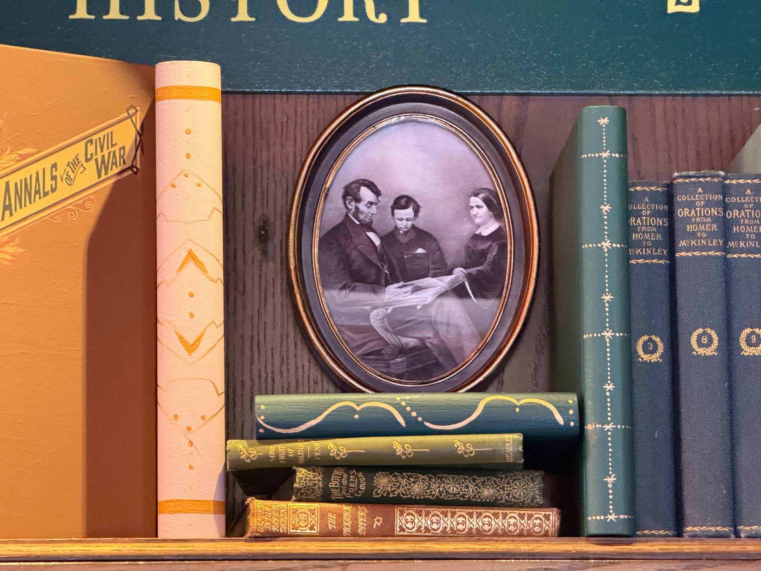 Framed black-and-white photo of three people sits on a bookshelf with vintage books, similar to Main Street U.S.A. displays at Disney parks.