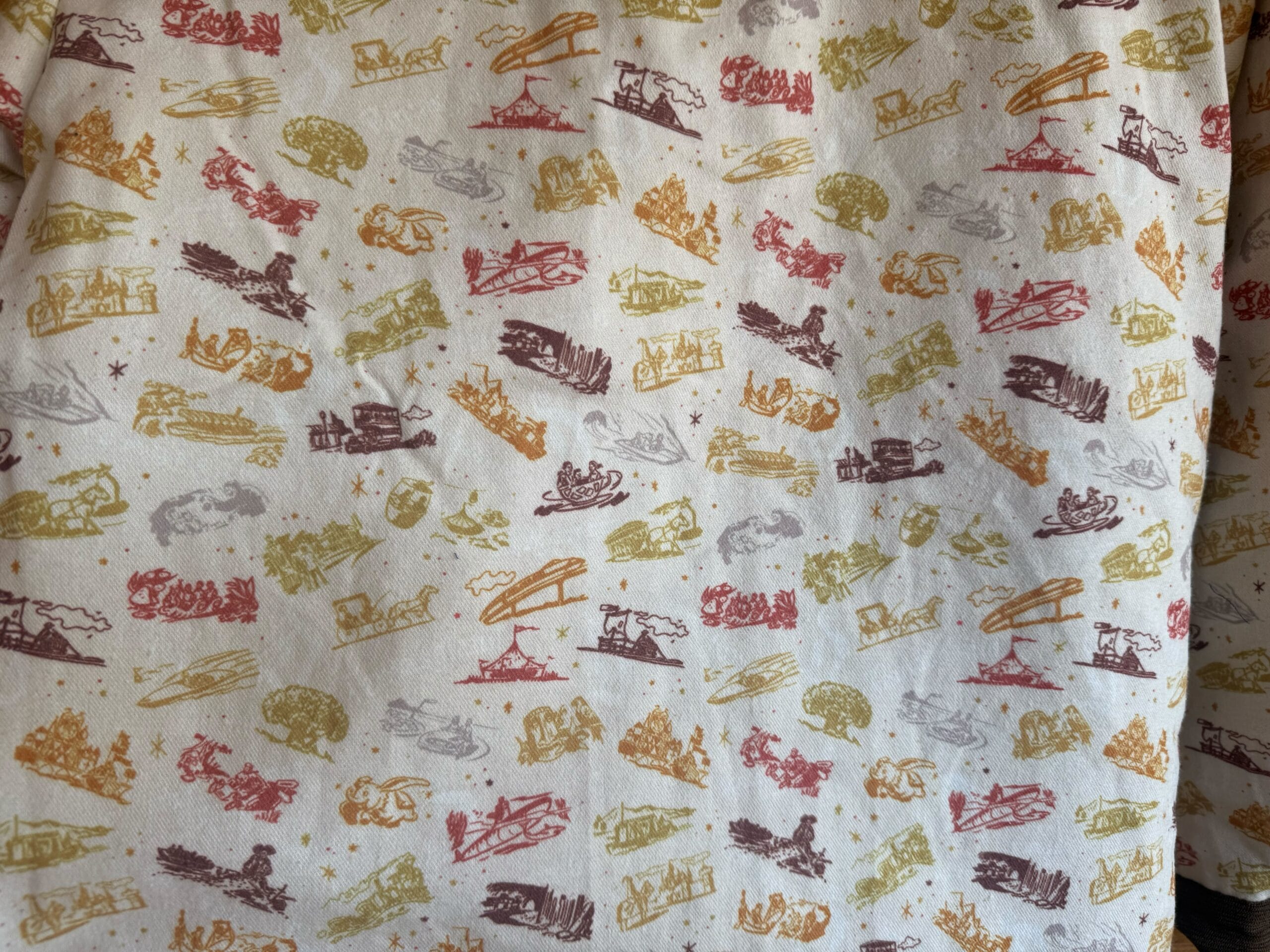 Patterned fabric featuring yellow, red, and brown sketches of vintage vehicles, evoking the nostalgic charm found in Disney park decor.