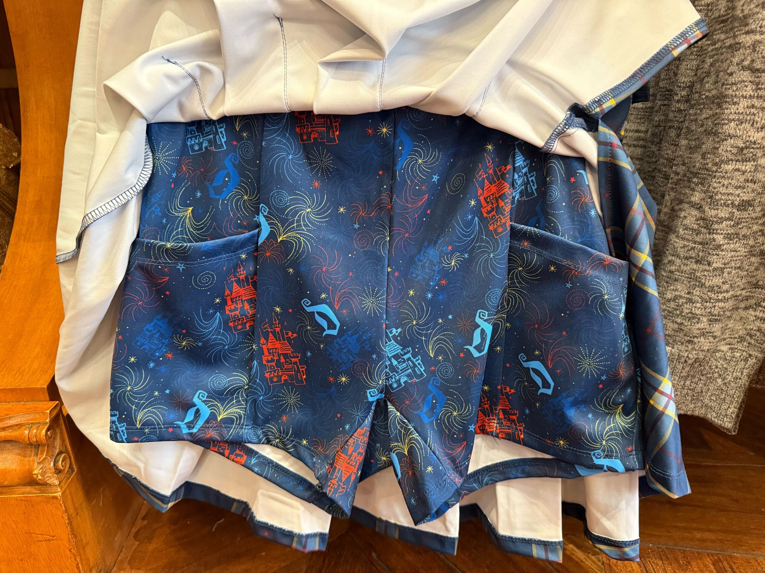 Blue shorts on a rack with a red castle resembling Disneyland’s Sleeping Beauty Castle, yellow fireworks, and blue Mickey motifs.