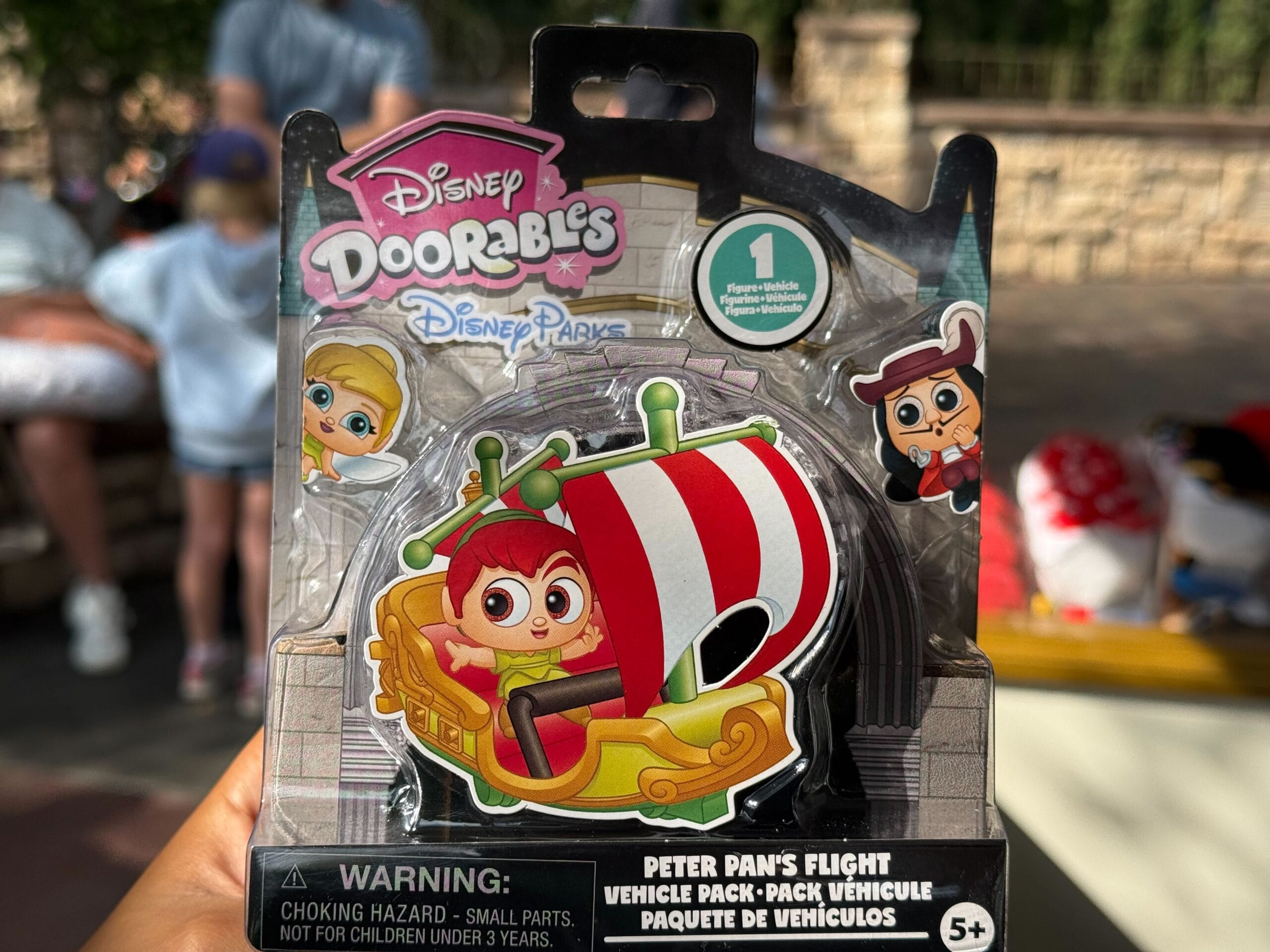 Guest displays a Disney Doorables Peter Pan’s Flight toy, packaging in hand, hinting at the magic of Disney parks beyond.