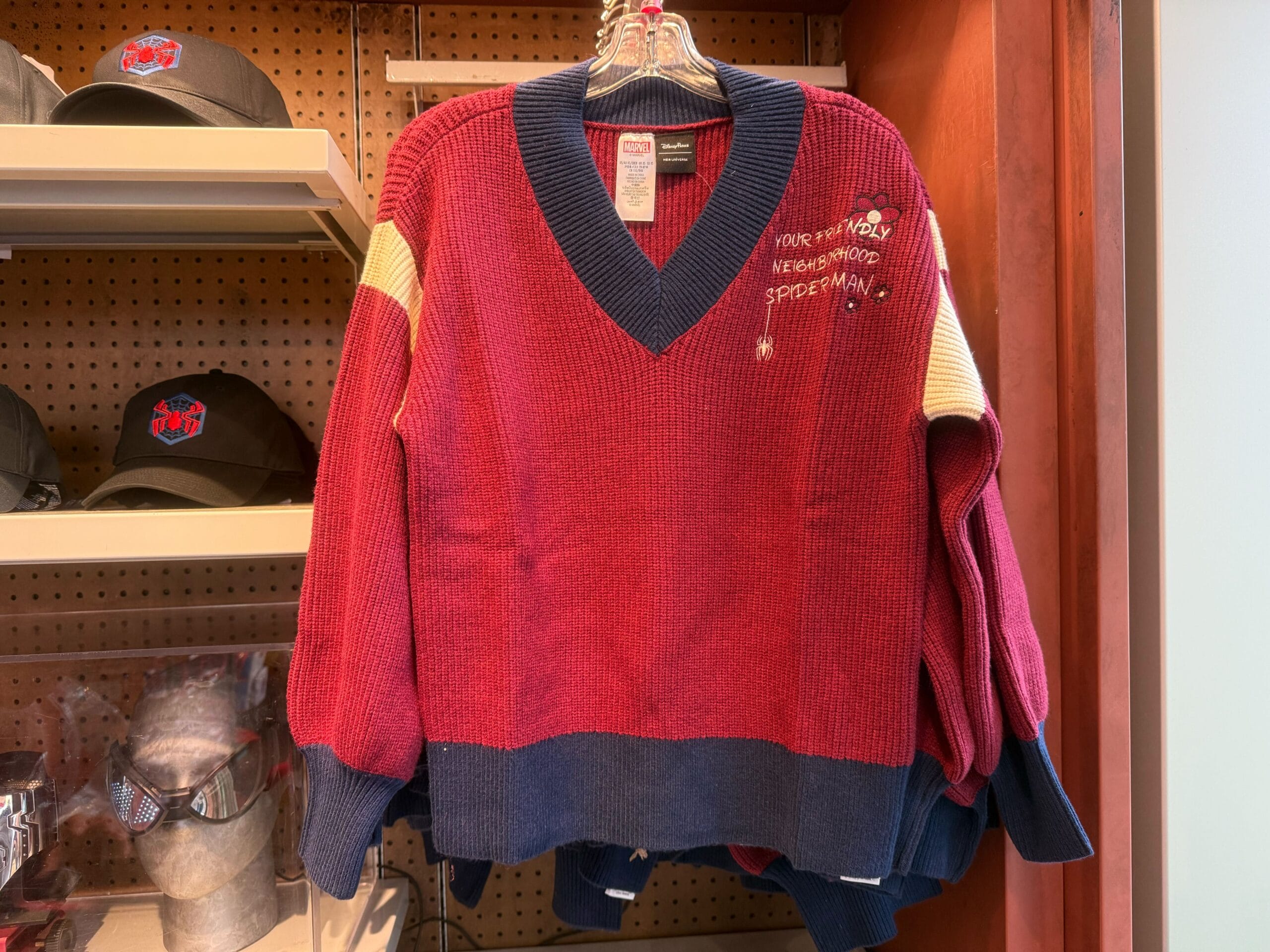 Red and navy Spider-Man sweater with "Your Friendly Neighborhood Spider-Man" on chest, spotted in a Disney park store display.