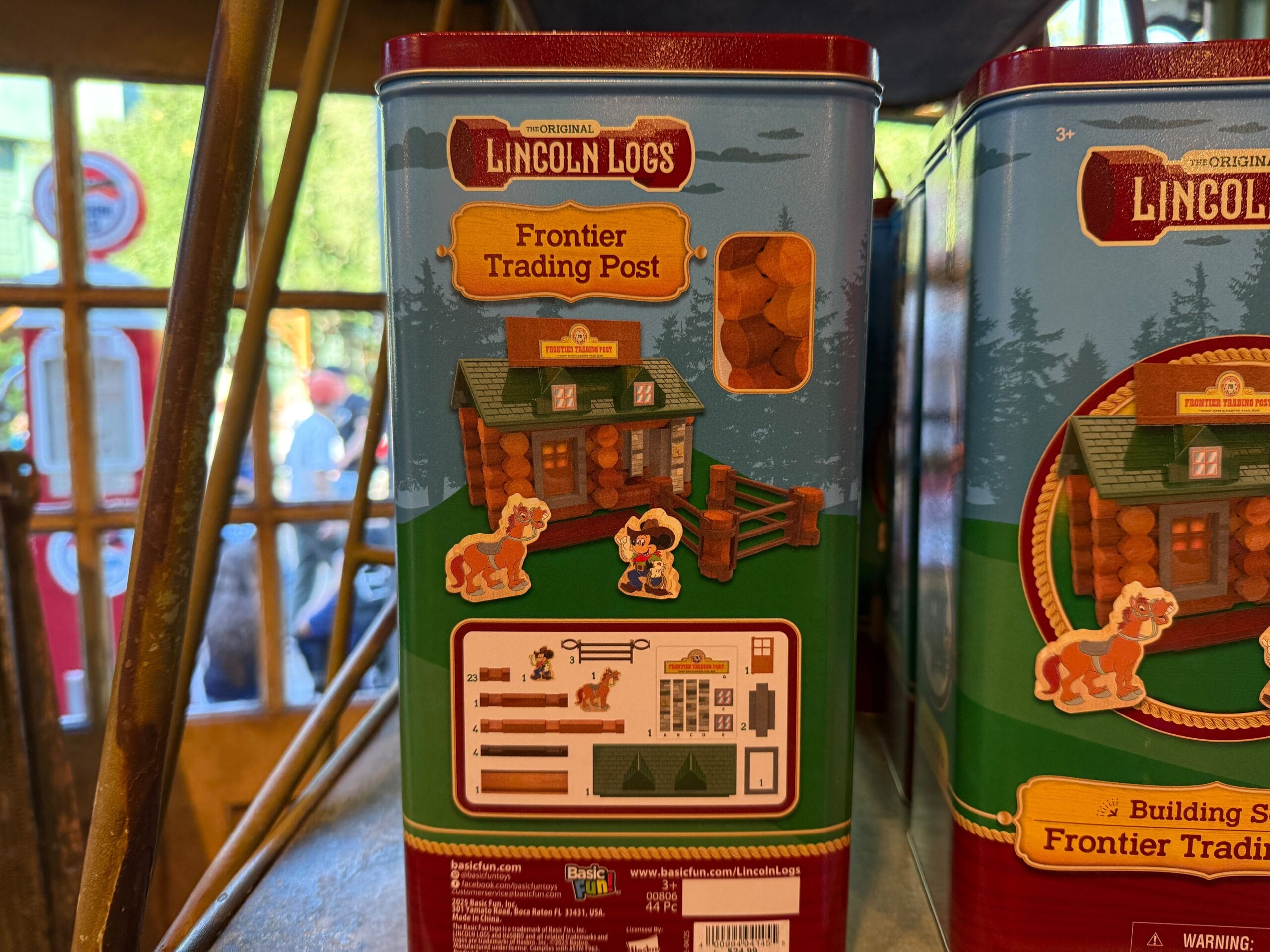 A Lincoln Logs Frontier Trading Post toy set tin, showing a log cabin illustration and kit contents on the side.
