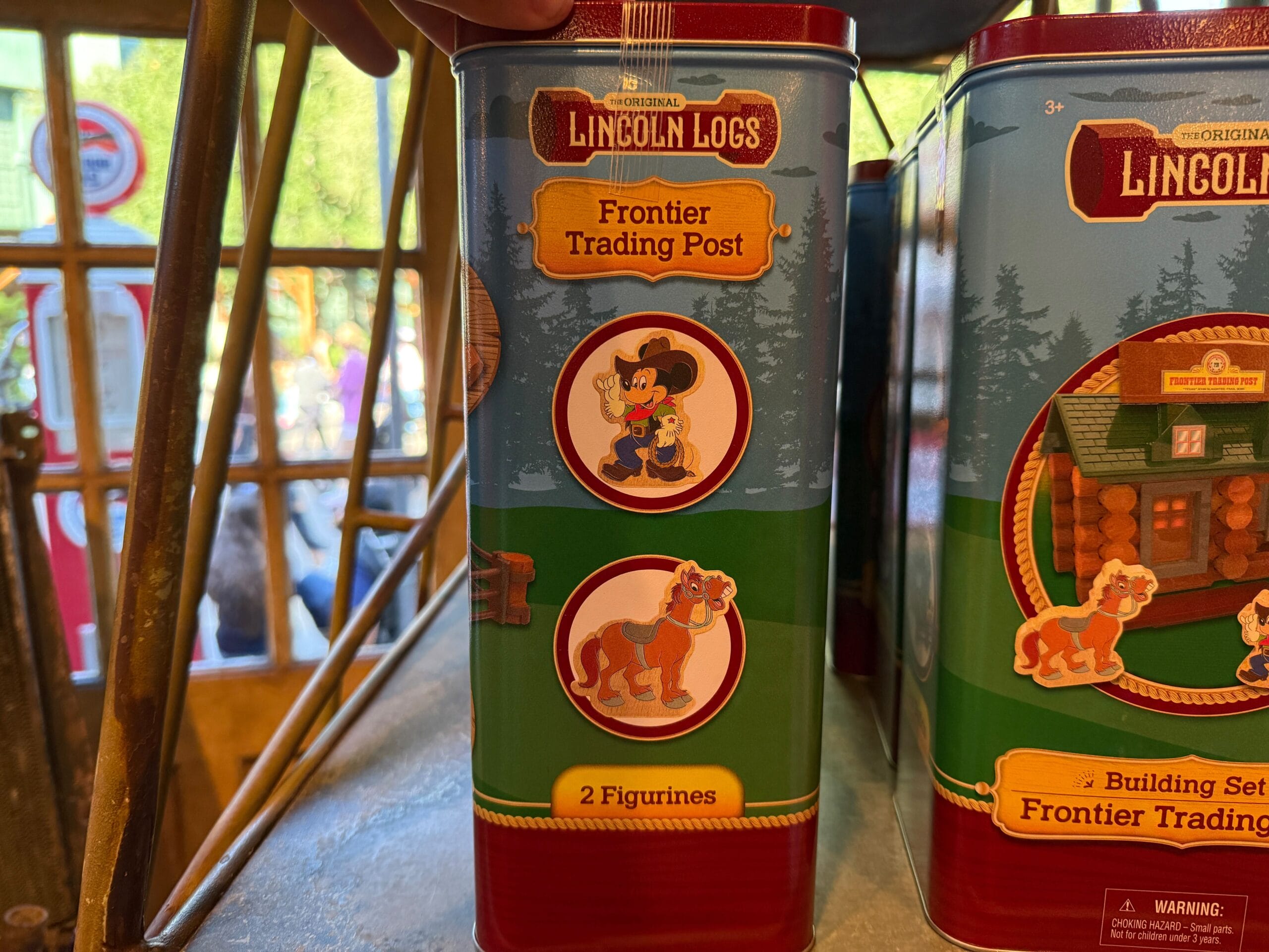 Lincoln Logs tin with illustrations of a cowboy and a horse, labeled "2 Figurines" and "Frontier Trading Post.