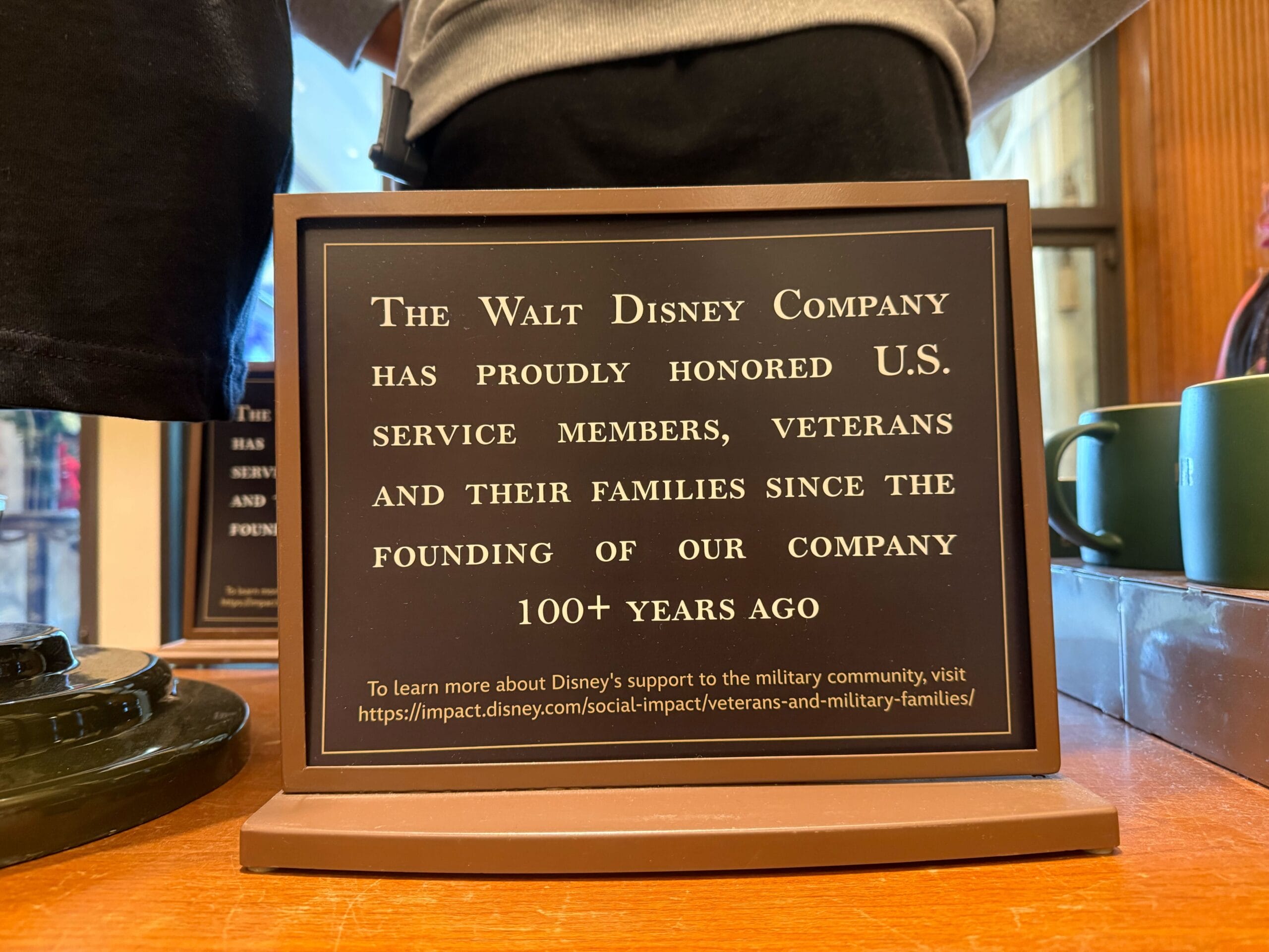 A sign in a store at Disneyland states "The Walt Disney Company has proudly honored U.S. service members, veterans and their families since the founding of our company 100+ years ago."