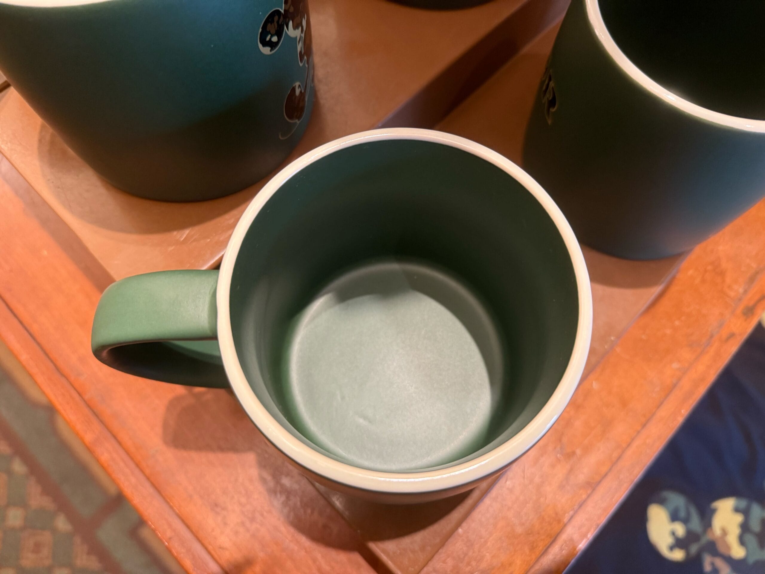 Green ceramic mug with handle, viewed from above on a wooden table.