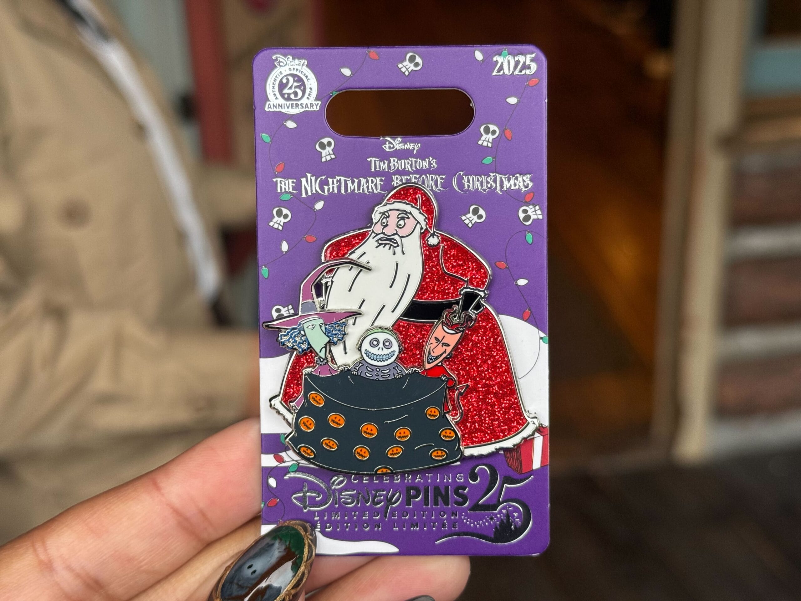 A hand displays a Disneyland Pin Tuesday pin of Nightmare Before Christmas' Santa with Lock, Shock, and Barrel.
