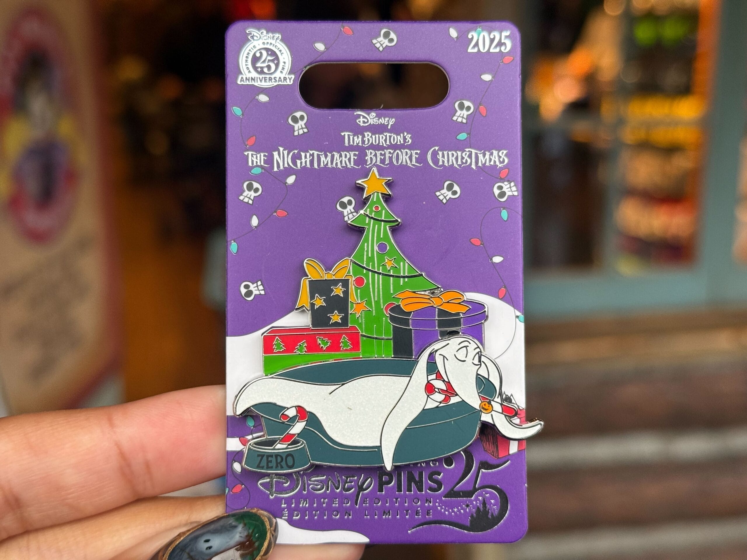 A hand displays a Disneyland Pin Tuesday find: Zero the ghost dog sleeping by a Christmas tree.
