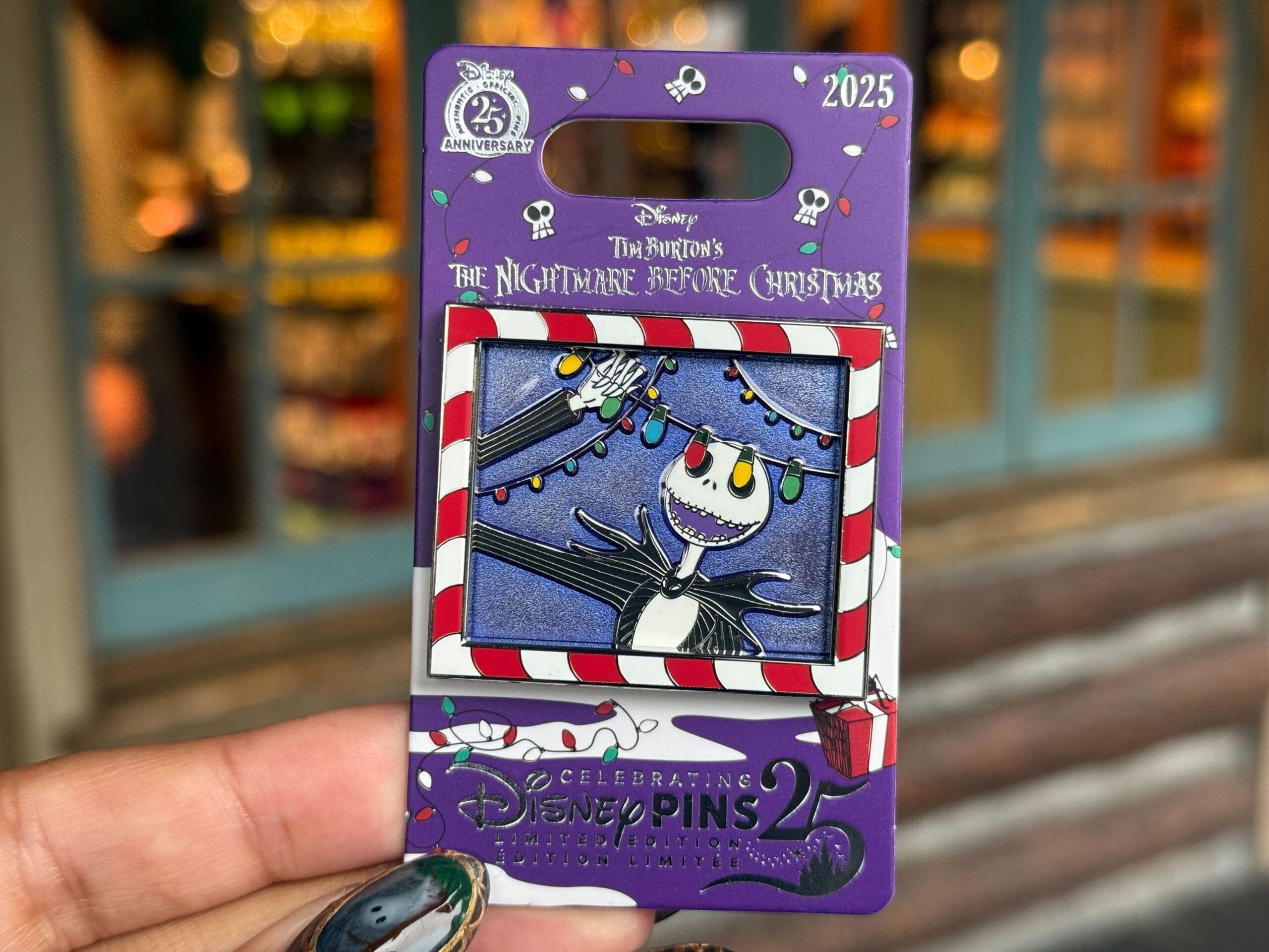 A hand holds a pin of Jack Skellington with Christmas lights from Nightmare Before Christmas.