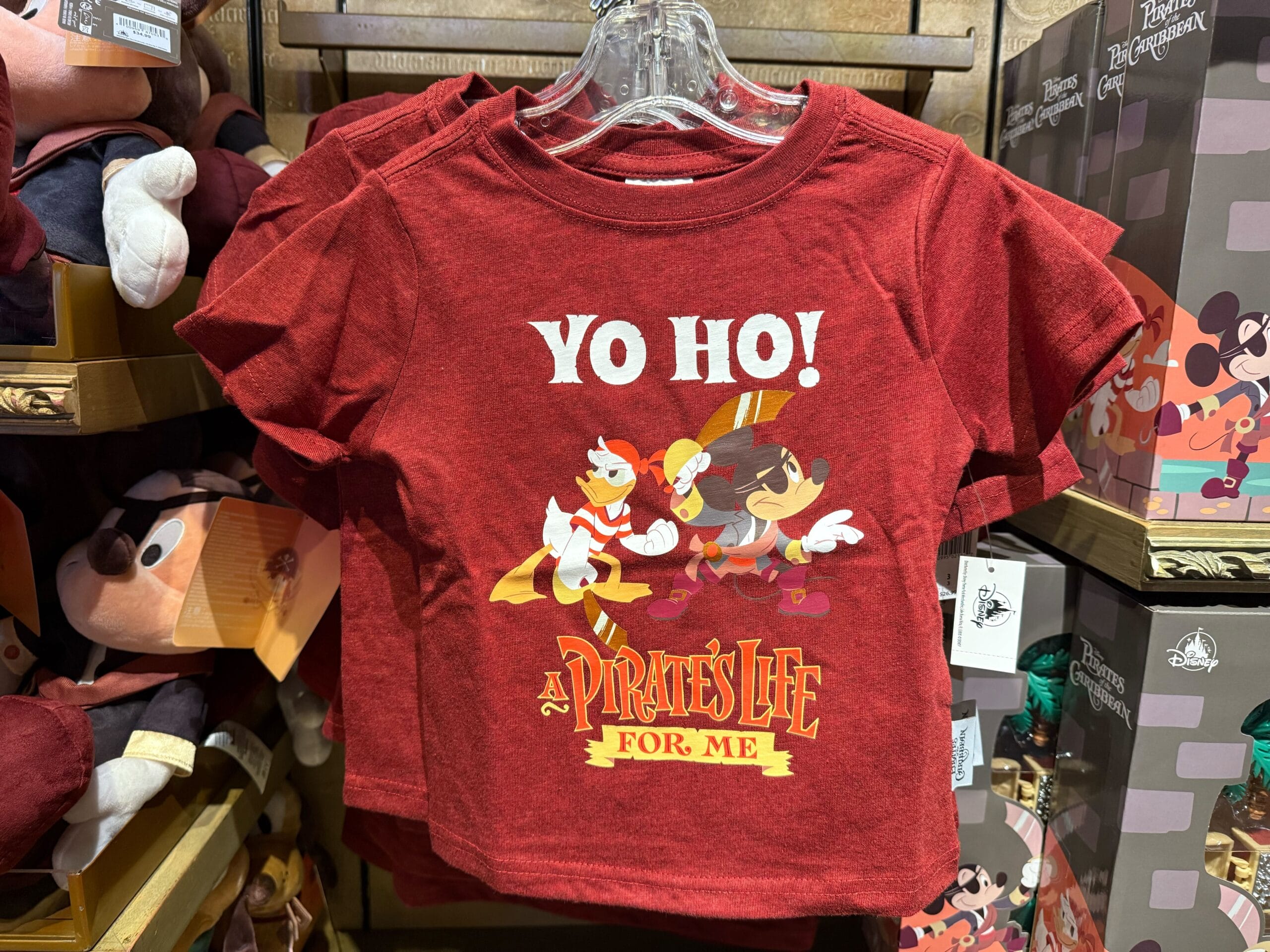 Red t-shirt featuring Donald Duck and Mickey Mouse as pirates, "Yo Ho! A Pirate's Life For Me." Seen in Disney Parks merchandise.