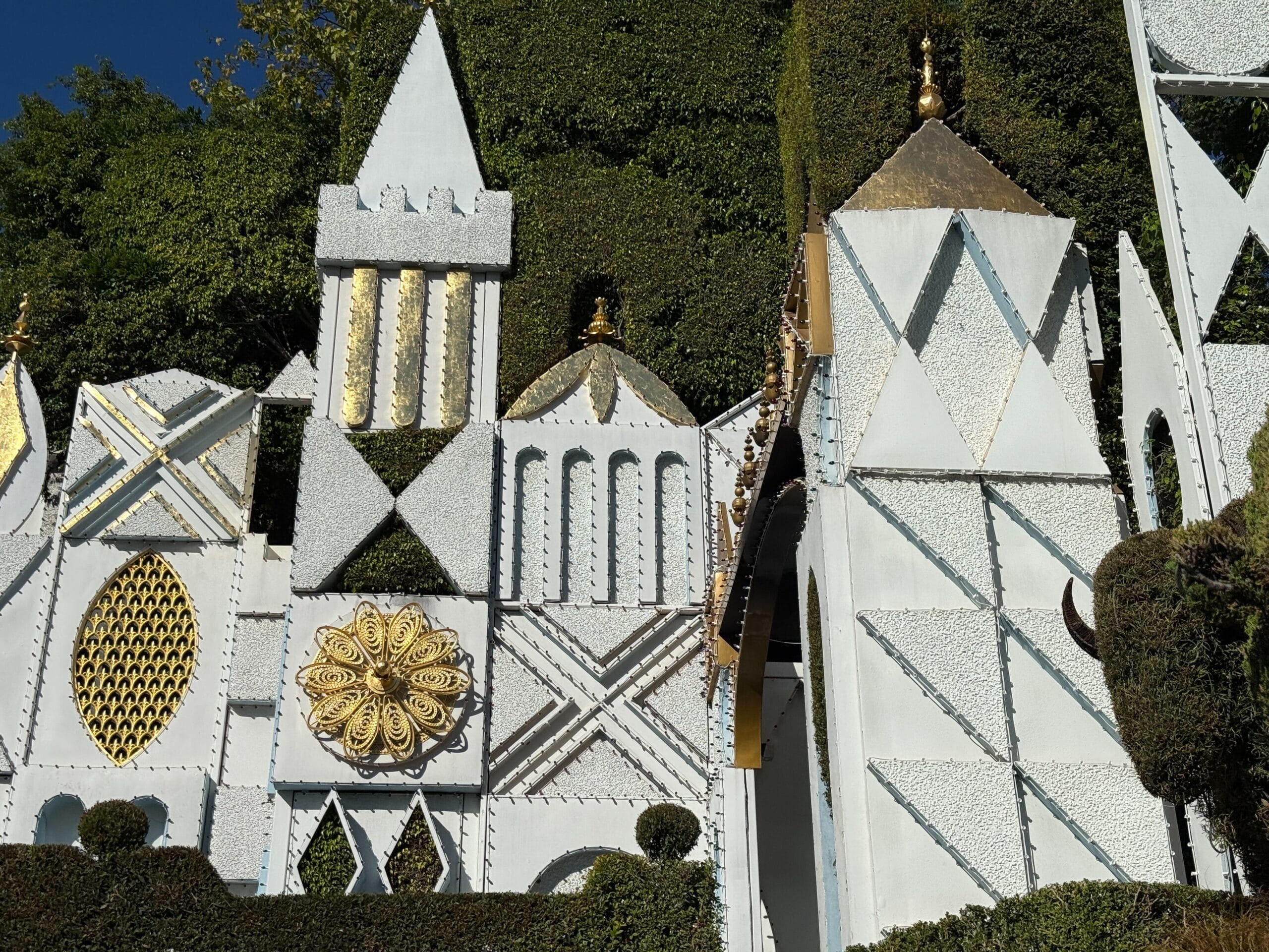 Whimsical white and gold geometric façade with greenery from Disneyland’s "It’s a Small World," distinct from any Disney castle.