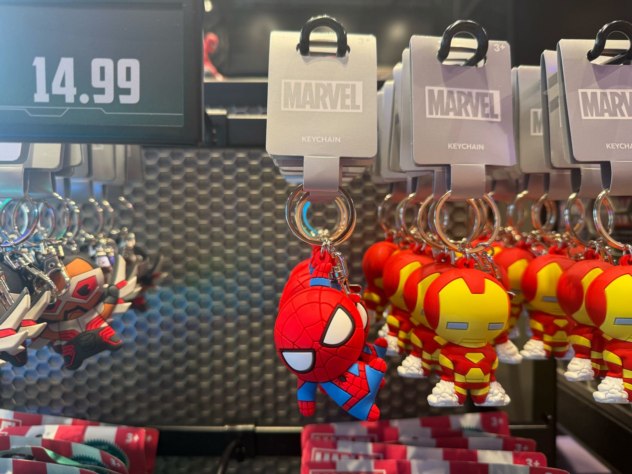 At Disneyland Resort: Spider-Man and Iron Man keychains, $14.99 each, displayed on a shop rack—magical park exclusives.