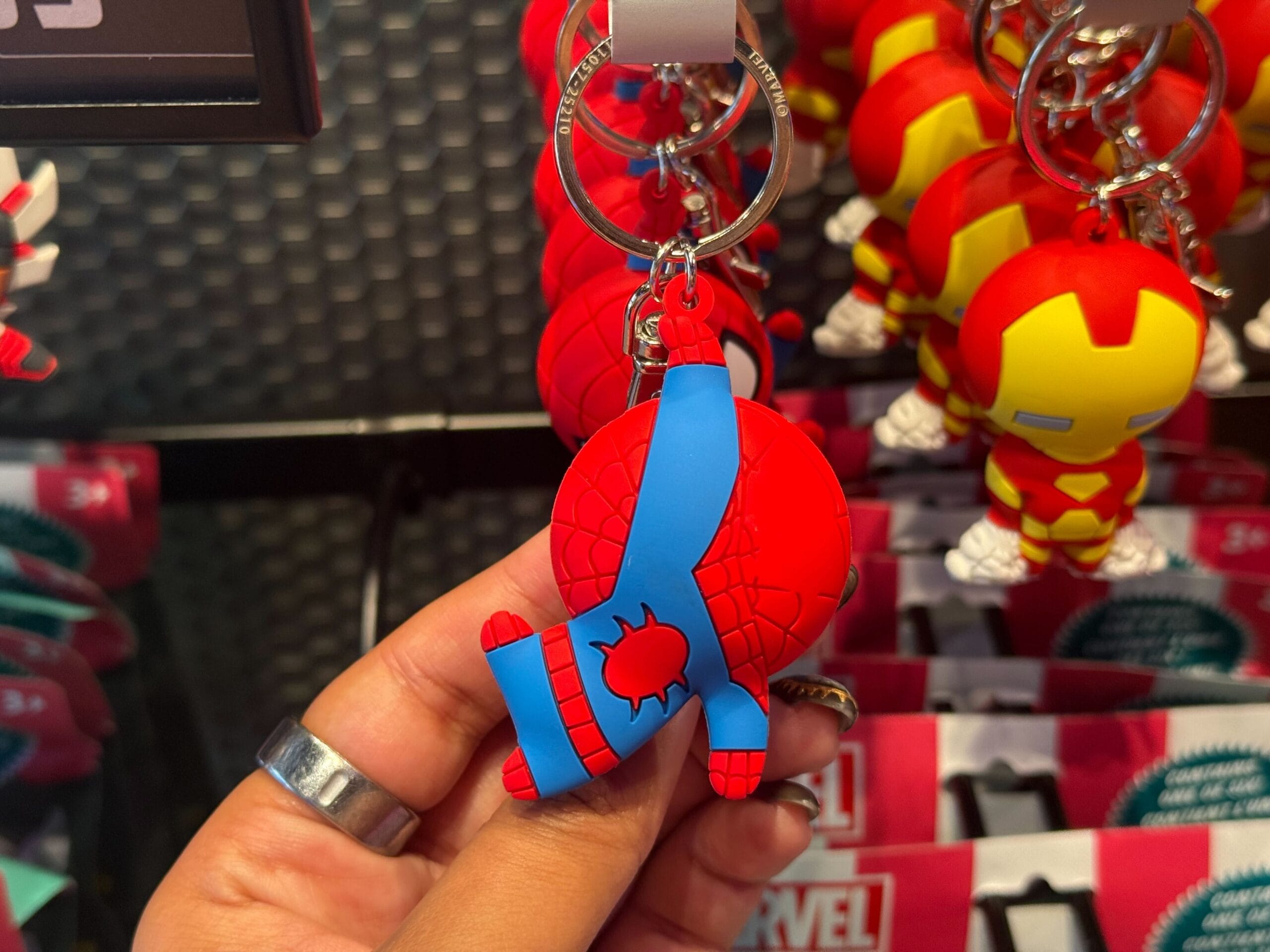 A hand displays a Spider-Man keychain among fresh merchandise at Disneyland Resort—no castle in view to compare with other Disney parks.