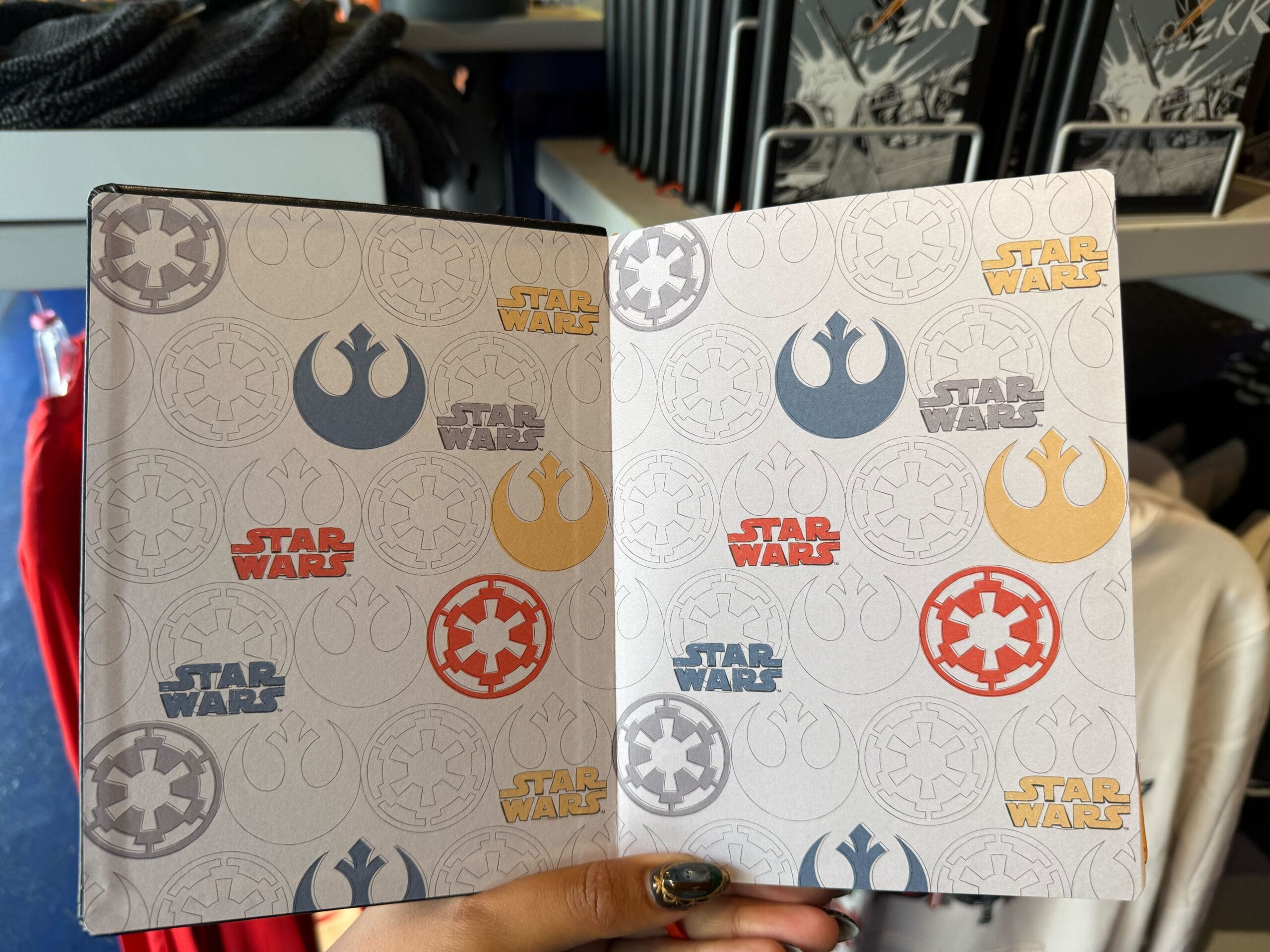 Open notebook showing repeated Star Wars logos and Darth Vader emblems inside, reminiscent of themed merchandise at Disney Parks.