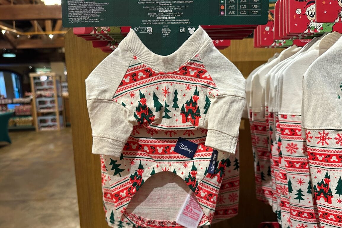 یک لباس حیوان خانگی شاد با طرح درختان کریسمس و الگوهای قرمز در میان کالاهای تعطیلات در یک فروشگاه هدیه پارک‌های دیزنی به نمایش گذاشته شده است.