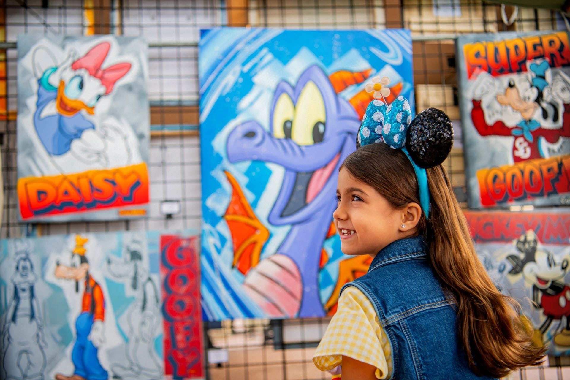 A young girl in Minnie Mouse ears beams at vibrant Disney art at EPCOT, one of Disney's unique parks without a castle centerpiece.