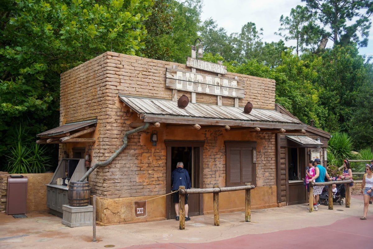 A rustic, brown brick eatery with a wooden "Golden Oak Outpost" sign in Magic Kingdom.