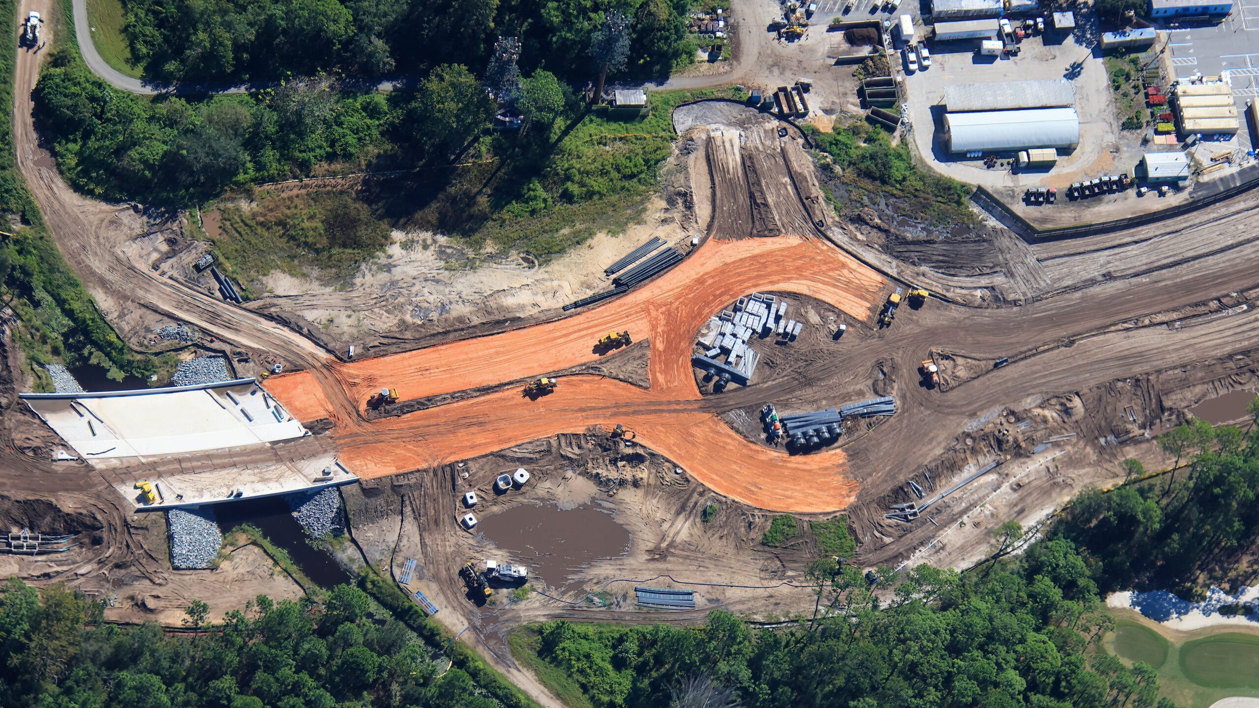 Aerial view of road work with traffic circle, machinery, and materials by trees and Grand Floridian, near Magic Kingdom at Disney World.