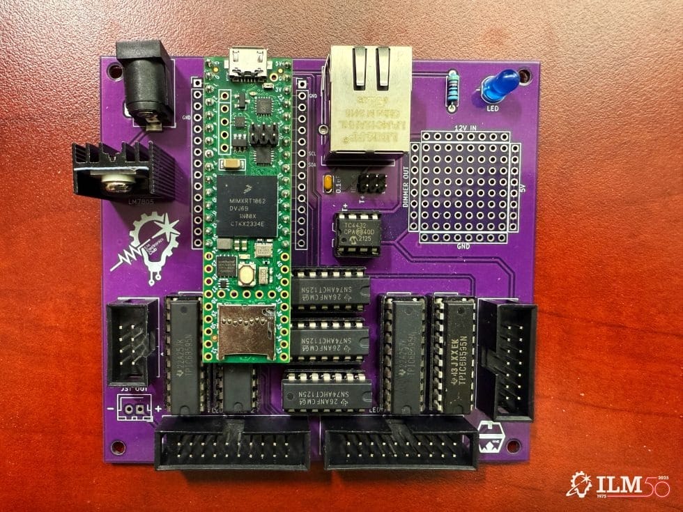 A purple circuit board with connectors and a green microcontroller sits on wood, evoking Tomorrowland tech at Disneyland parks.