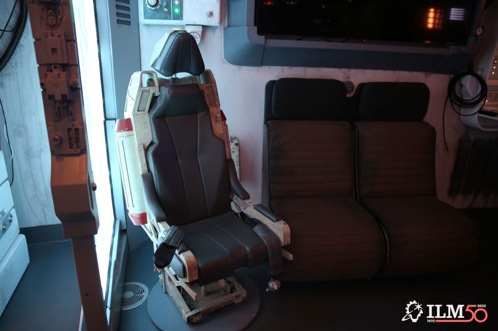 Futuristic pilot seat next to a dark sofa in a Star Wars lounge, ILM 50th logo—evokes Disney Parks' immersive galaxy theming.