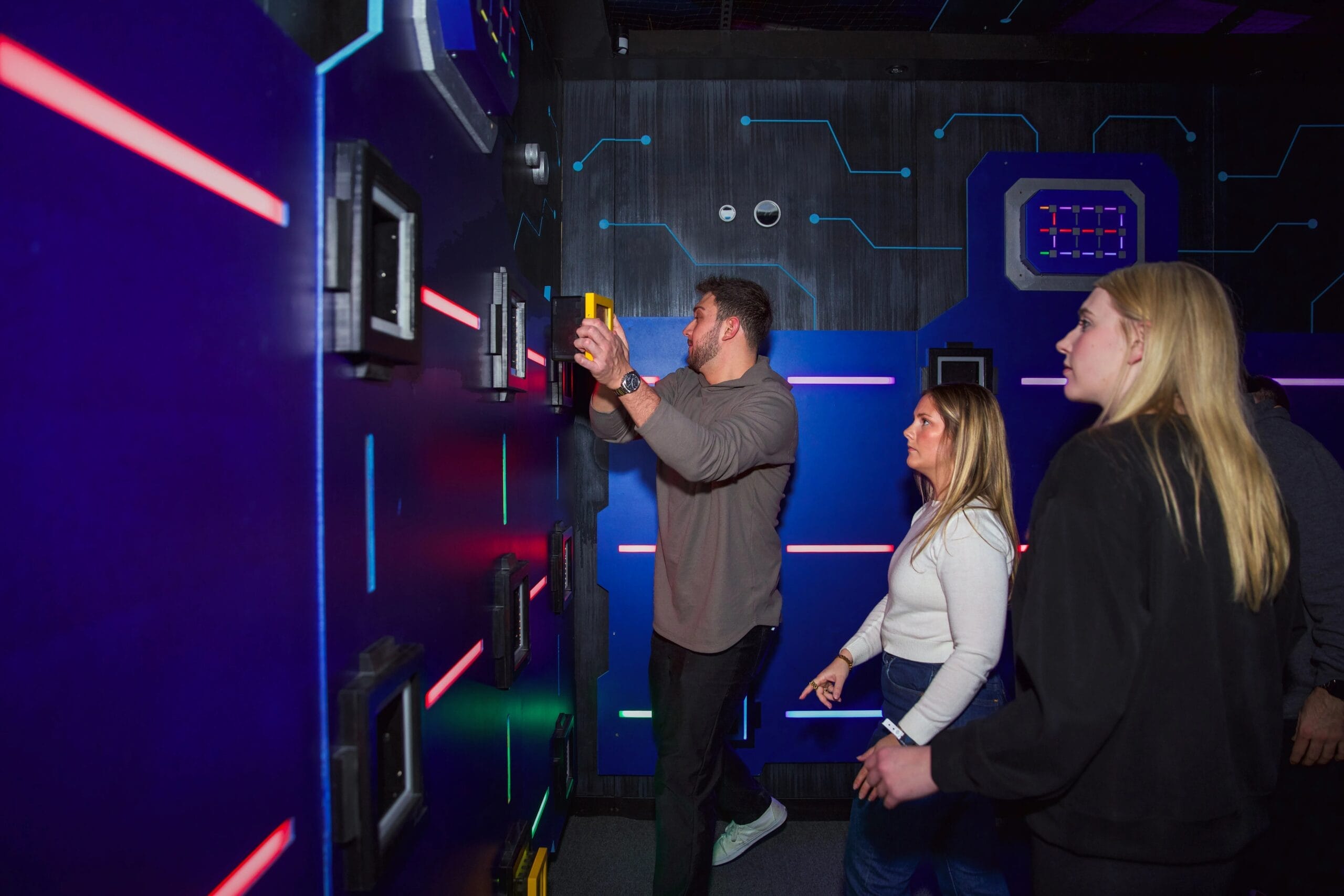 Three guests play at a glowing Level99 game wall.