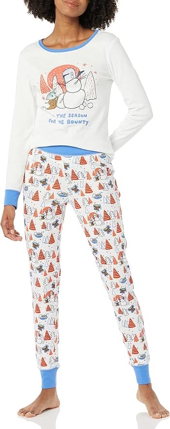 Woman wearing matching winter-themed pajamas with a Grogu and snowman print.