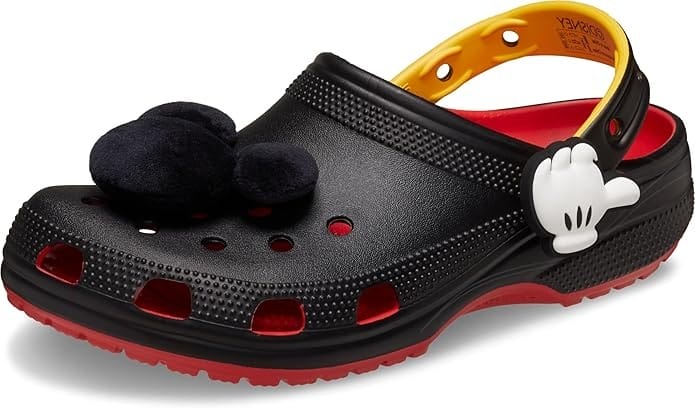A Mickey Mouse-inspired Crocs classic clog with black body, red sole, and large fuzzy Mickey Mouse head charm.