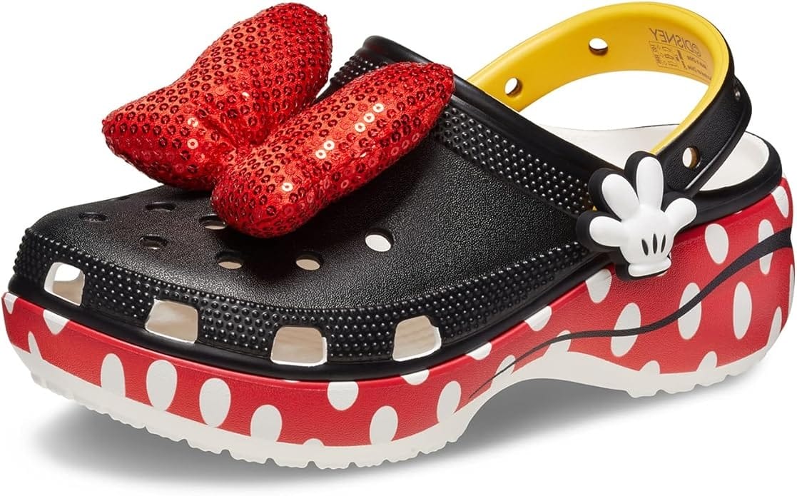 A Minnie Mouse-inspired platform Crocs clog with red and white polka dot sole, black upper, and large red sequin bow charm.