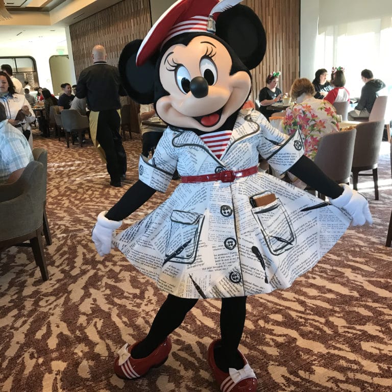 Minnie Mouse poses in a white dress with black sketches at a top Disney World character meal, castle not pictured for comparison.