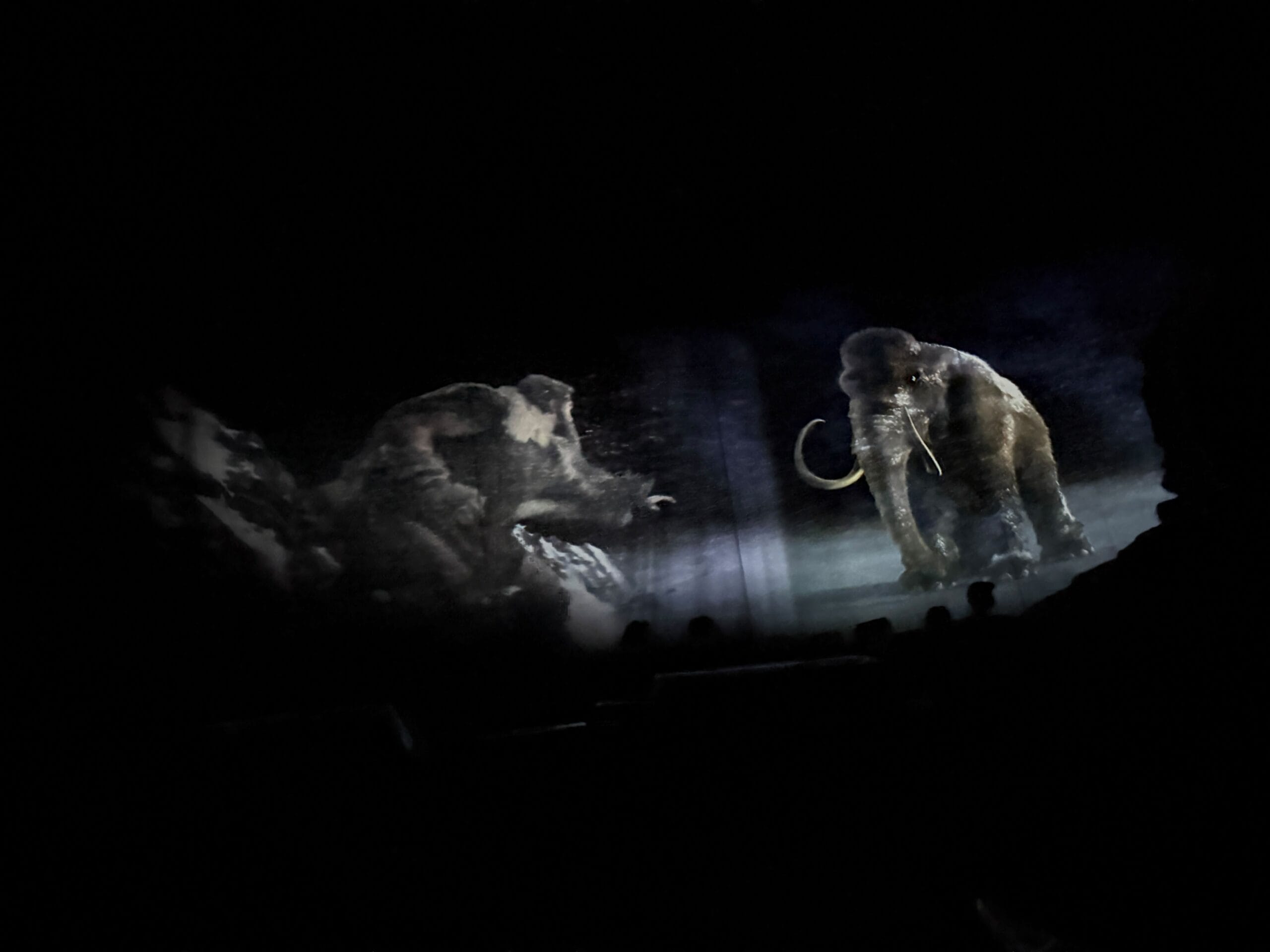 Two woolly mammoths face off in a dark, misty scene evoking Spaceship Earth’s diorama at Epcot, not a Disney castle.