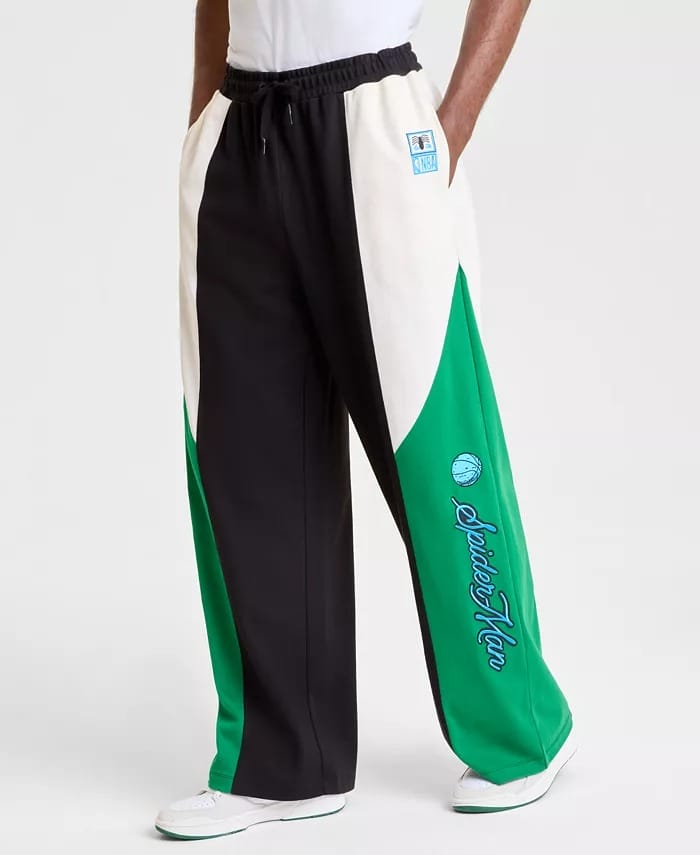 Person wearing Disney-inspired wide-leg pants with black, white, and green panels and "Spider-Man" text at a Disney park.