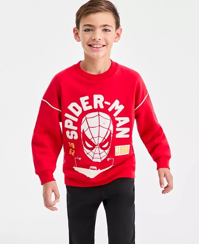 Smiling boy in a red Spider-Man sweatshirt and black pants, like you'd spot near Main Street, stands before a plain white background.