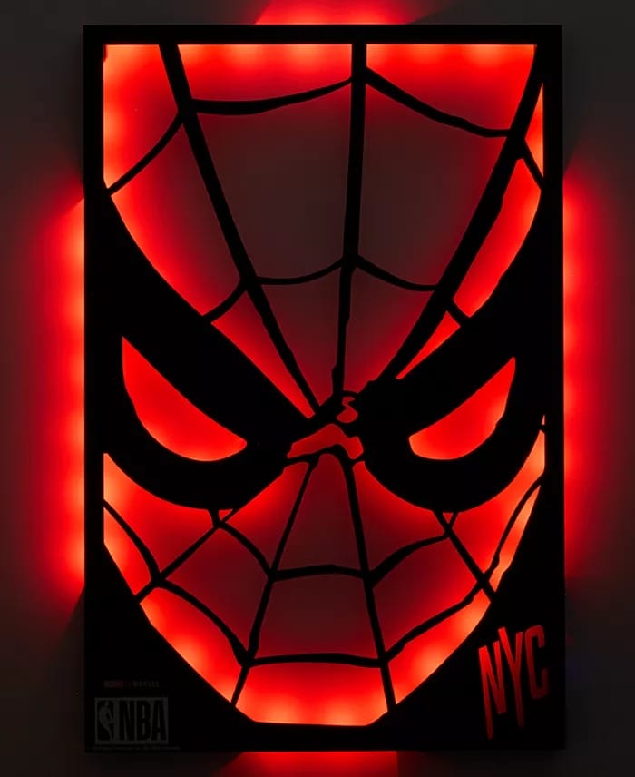 Red neon Spider-Man face art glows with NYC and NBA logos, evoking Marvel vibes seen in Disney Parks, set to a dark backdrop.