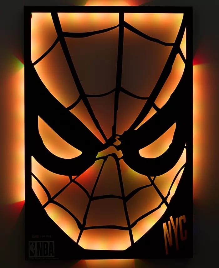 Glowing Spider-Man face with orange-yellow lights, NBA and NYC logos, Macy's Collection—no Disney castle elements present.