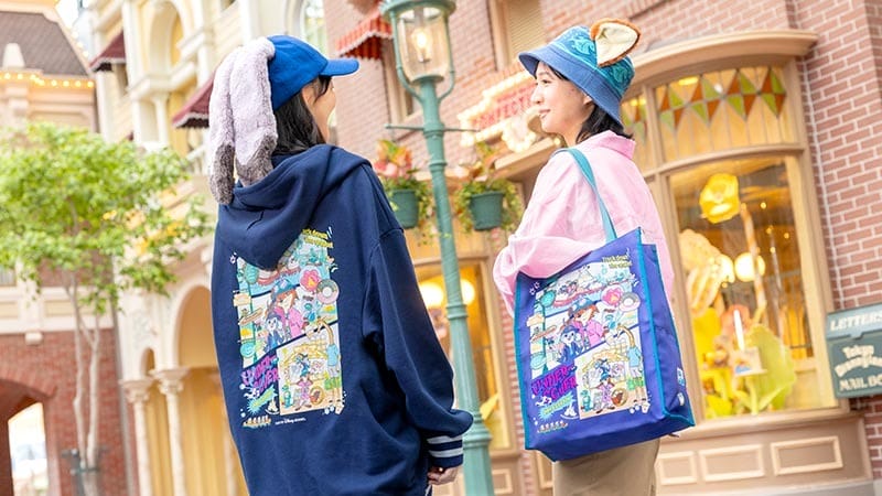 Two visitors in colorful hats and jackets display Duffy and Friends goods outside a Tokyo Disneyland shop—no castle in sight.