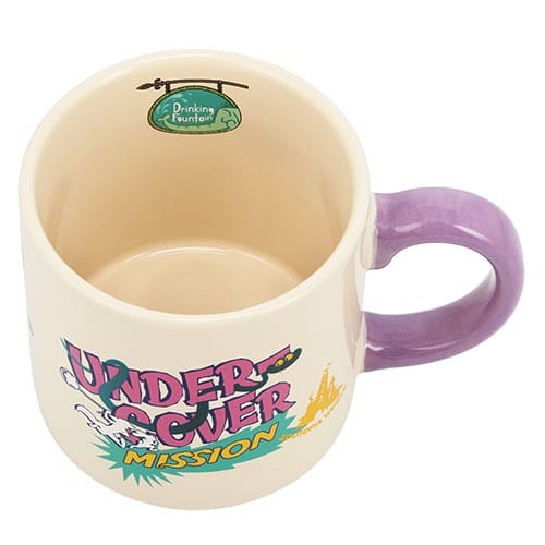 A cream mug with a purple handle from Tokyo Disneyland, featuring "UNDERCOVER MISSION" and "Drinking Fountain" inside.