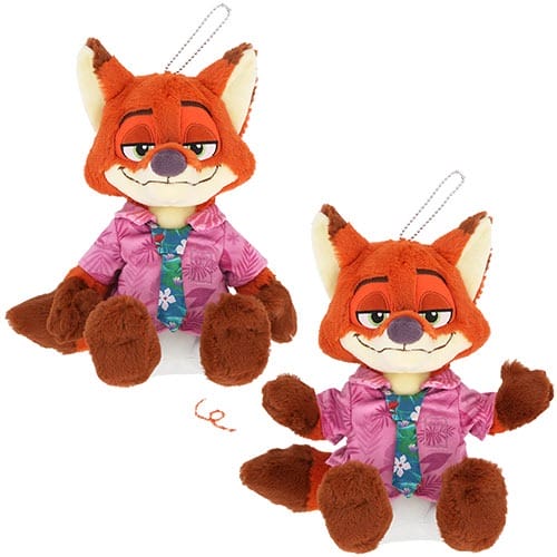 Two plush fox toys with orange fur and purple shirts smiling, sold as Zootopia 2 keychains at a Disney park, no castle shown.