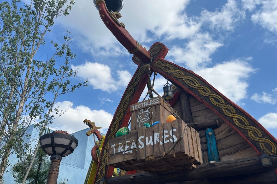 A wooden Viking ship with a Toothless' Treasures crate and colorful eggs, set beneath a bright sky like one at Epcot’s Norway Pavilion.