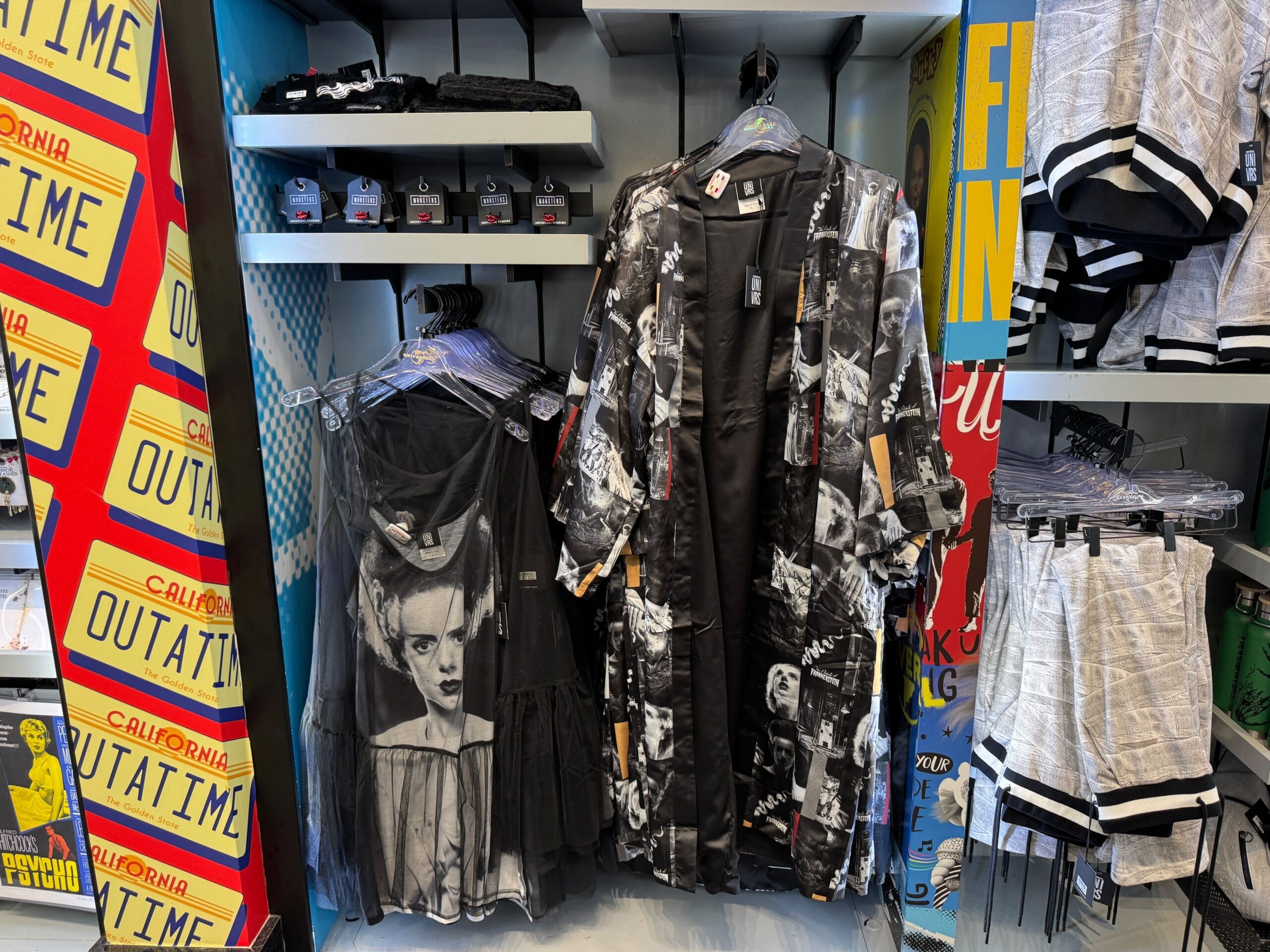 Clothing display with black-and-white horror dresses and newspaper-print shorts, similar to styles seen at Disney parks boutiques.