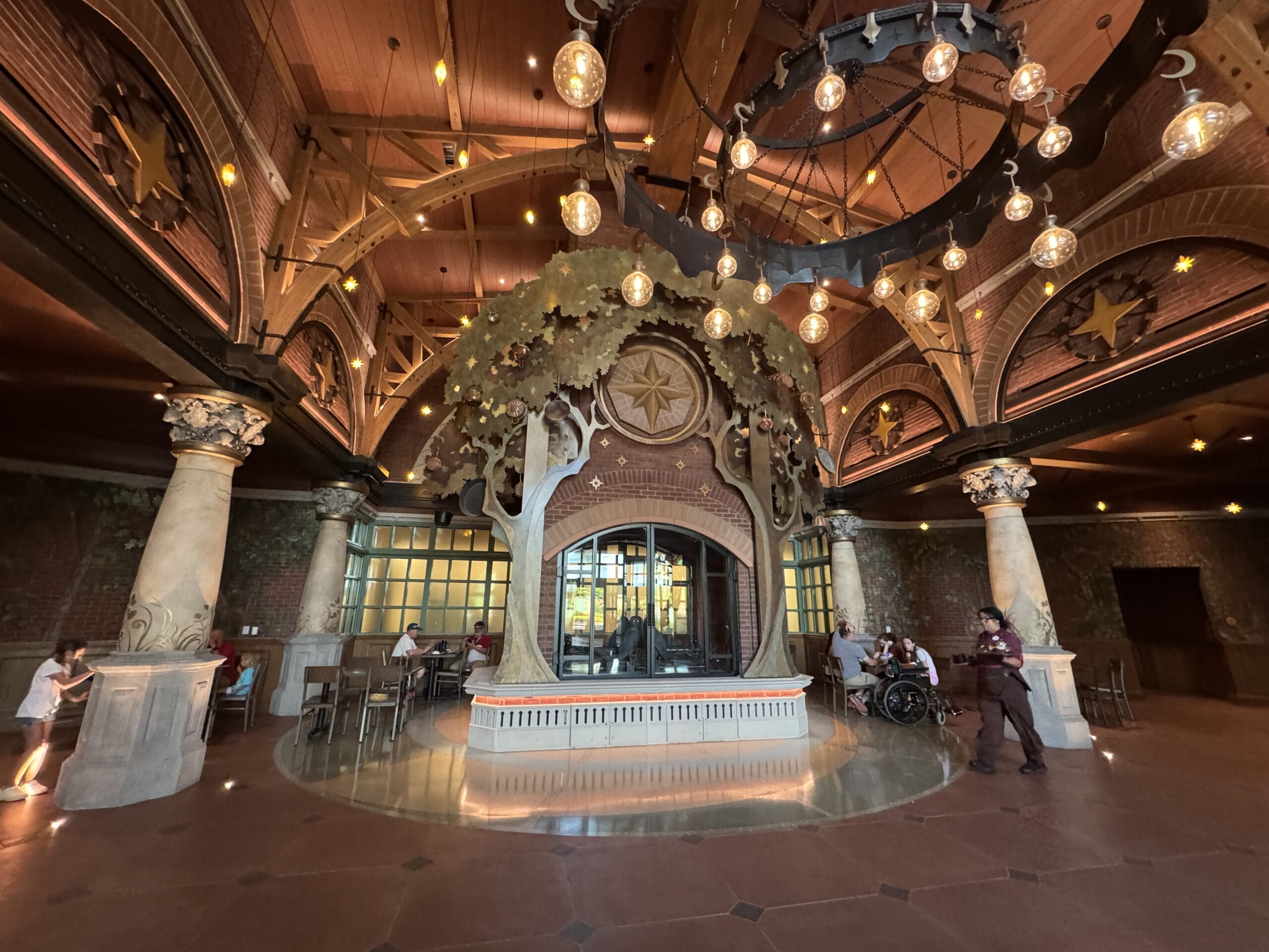 Grand, whimsical Epic Universe hall with tree-like columns and stars; evokes Disney park magic but lacks iconic castles.