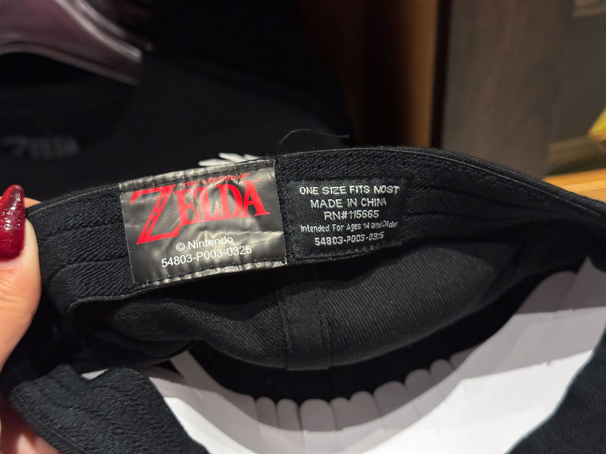 Black hat from Zelda Merchandise with inside label, "Zelda" logo, and "One size fits most"—an epic universe accessory.
