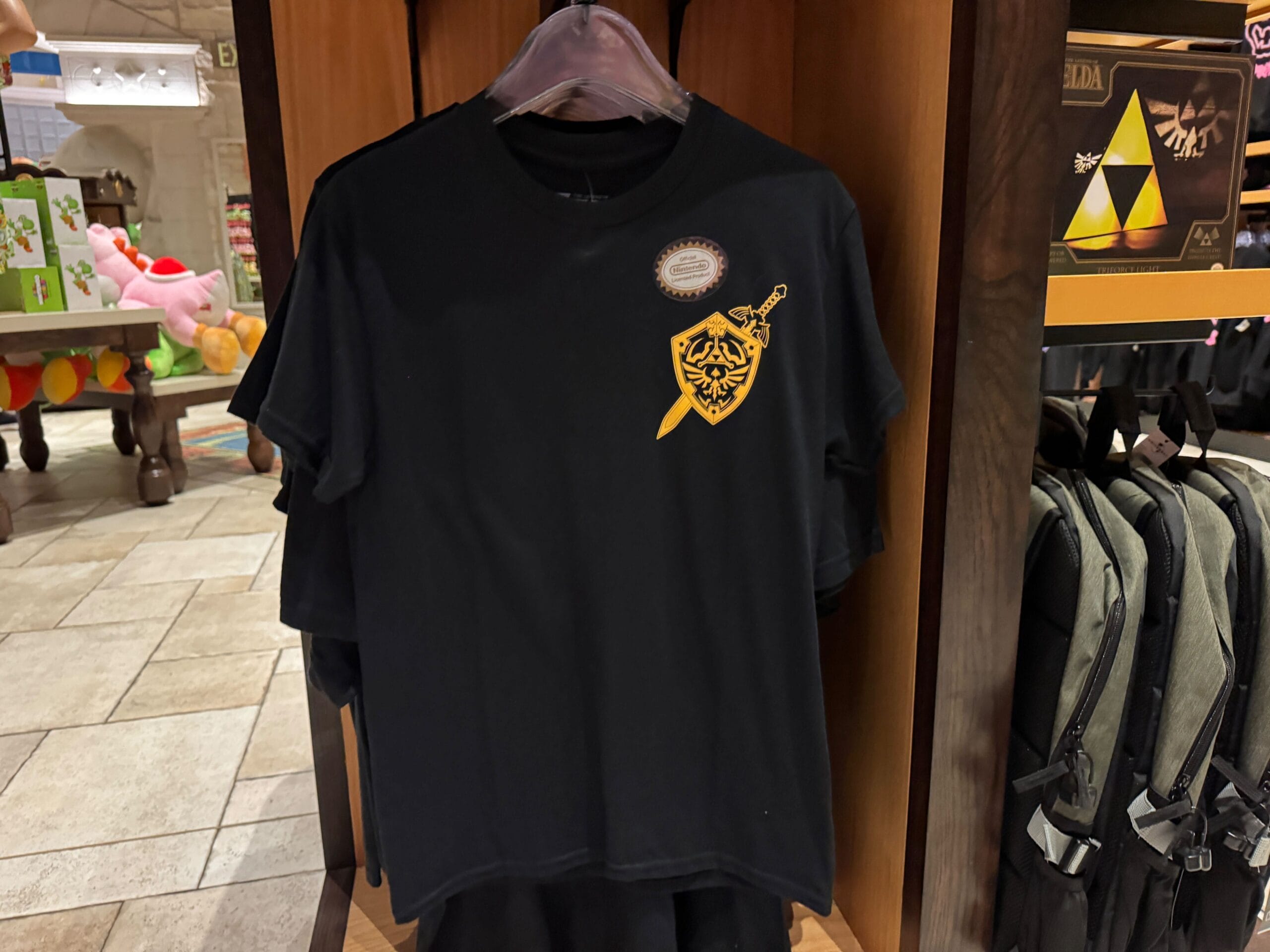 Black T-shirt with a yellow Legend of Zelda sword and shield emblem, perfect for any Zelda merchandise collection.