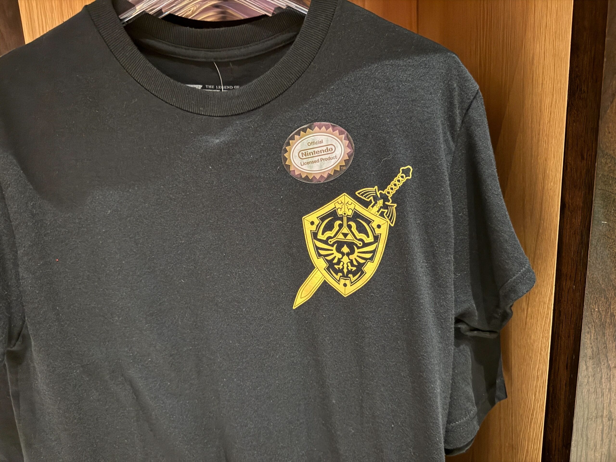 Black T-shirt with a yellow Legend of Zelda shield graphic—perfect Zelda merchandise for any epic universe adventurer.
