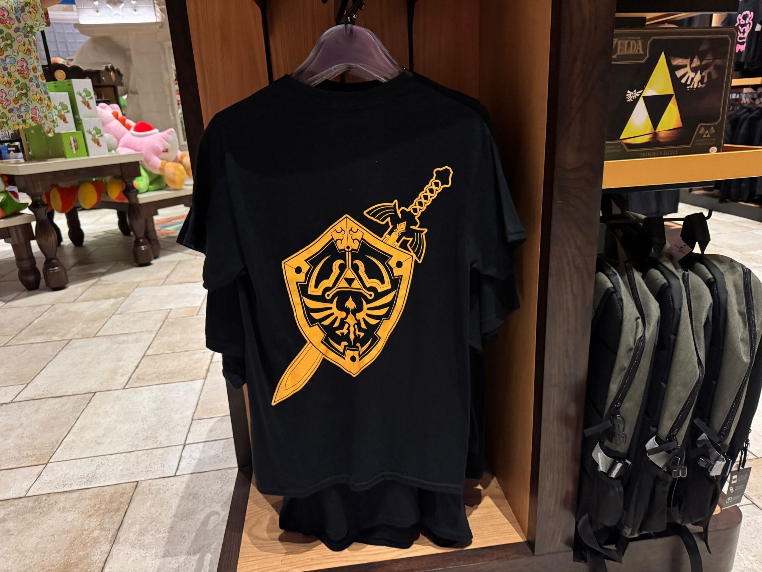 Black T-shirt with a yellow shield and sword graphic, perfect Zelda merchandise for any Epic Universe fan.