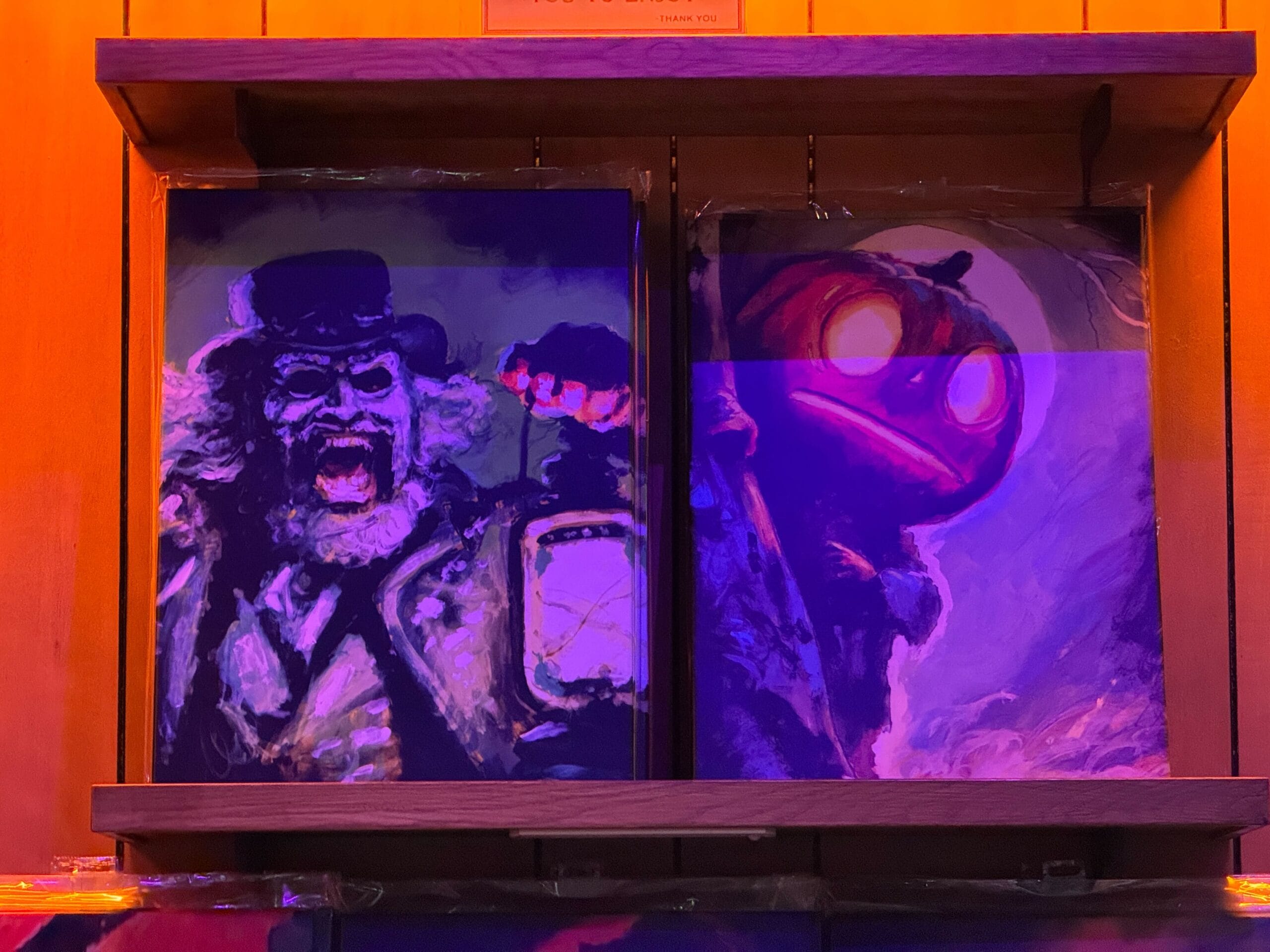 Two eerie paintings like those in Disney’s Haunted Mansion: a ghostly man with a lantern, and a glowing pumpkin-headed figure.