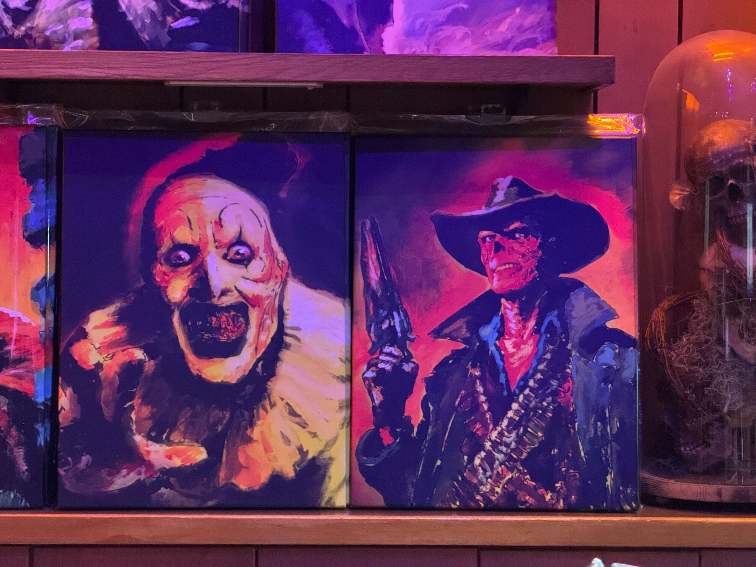 Two vibrant paintings: a mischievous clown resembling a Disneyland performer and a cowboy like those from Frontierland attractions.