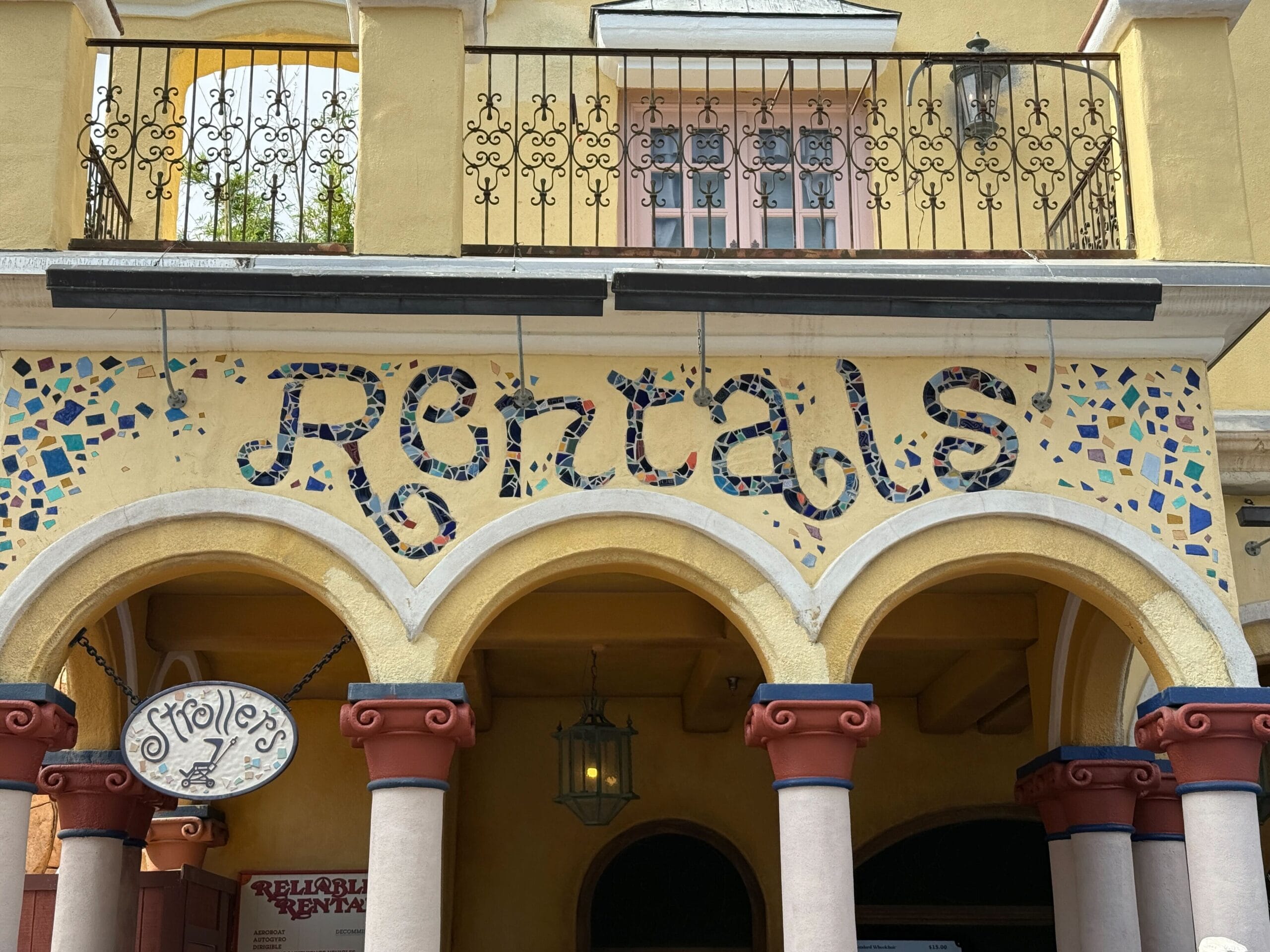 A building with mosaic-tiled arches and a large "Rentals" sign, similar to whimsical architecture found in Disney Parks.
