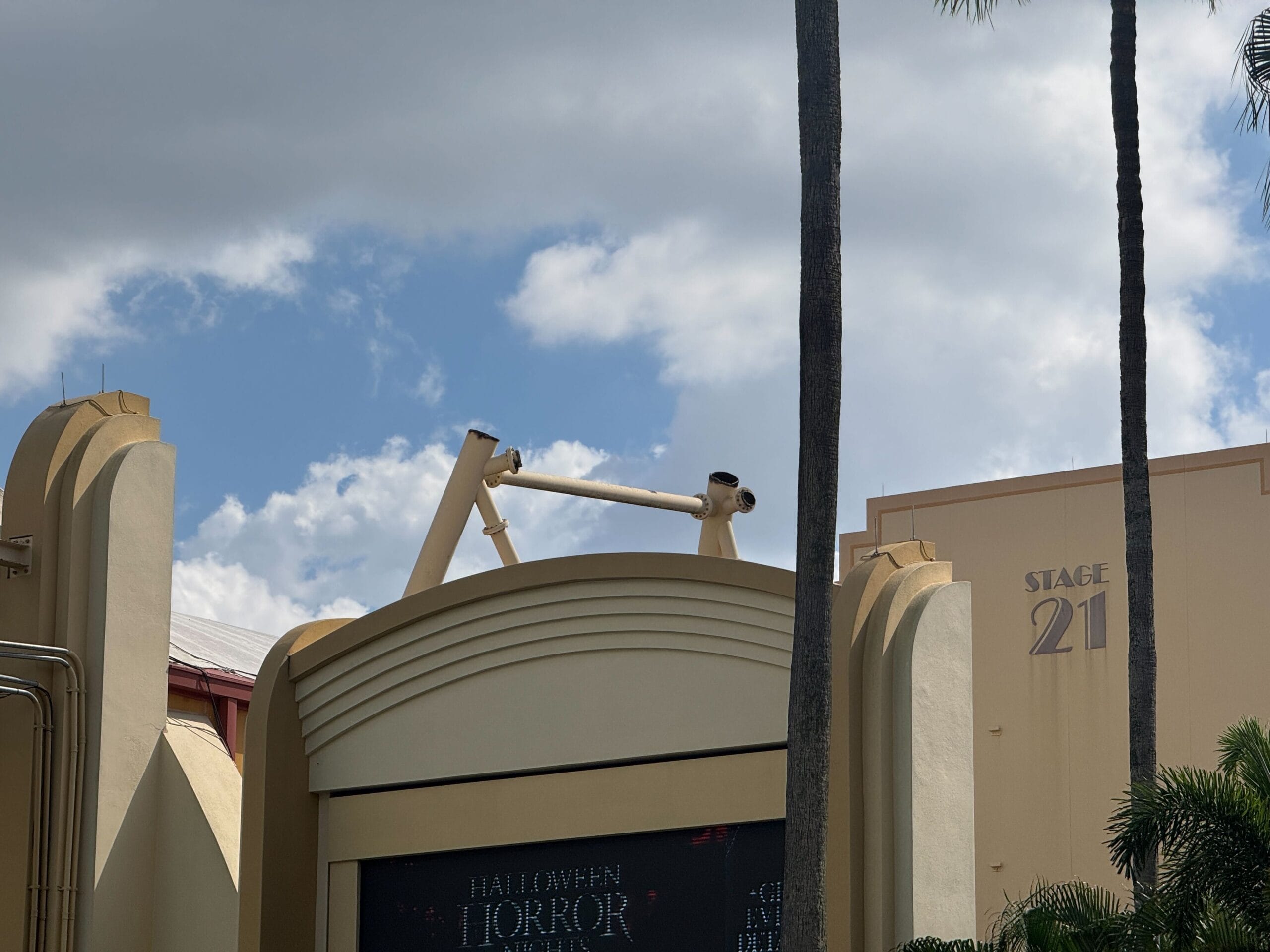 Art Deco building with "Stage 21" sign, near Hollywood Rip Ride Rockit at Universal Studios Florida, framed by palm trees.
