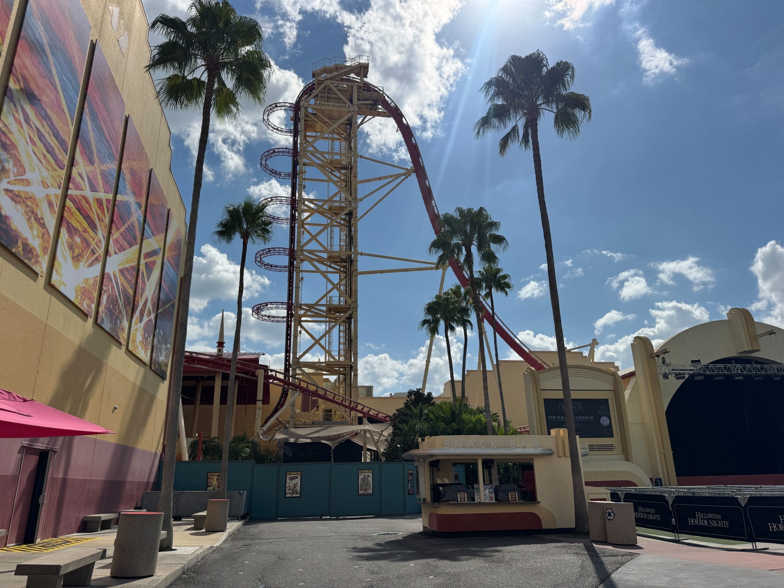 The Hollywood Rip Ride Rockit roller coaster towers behind palm trees at Universal Studios Florida under a sunny sky.